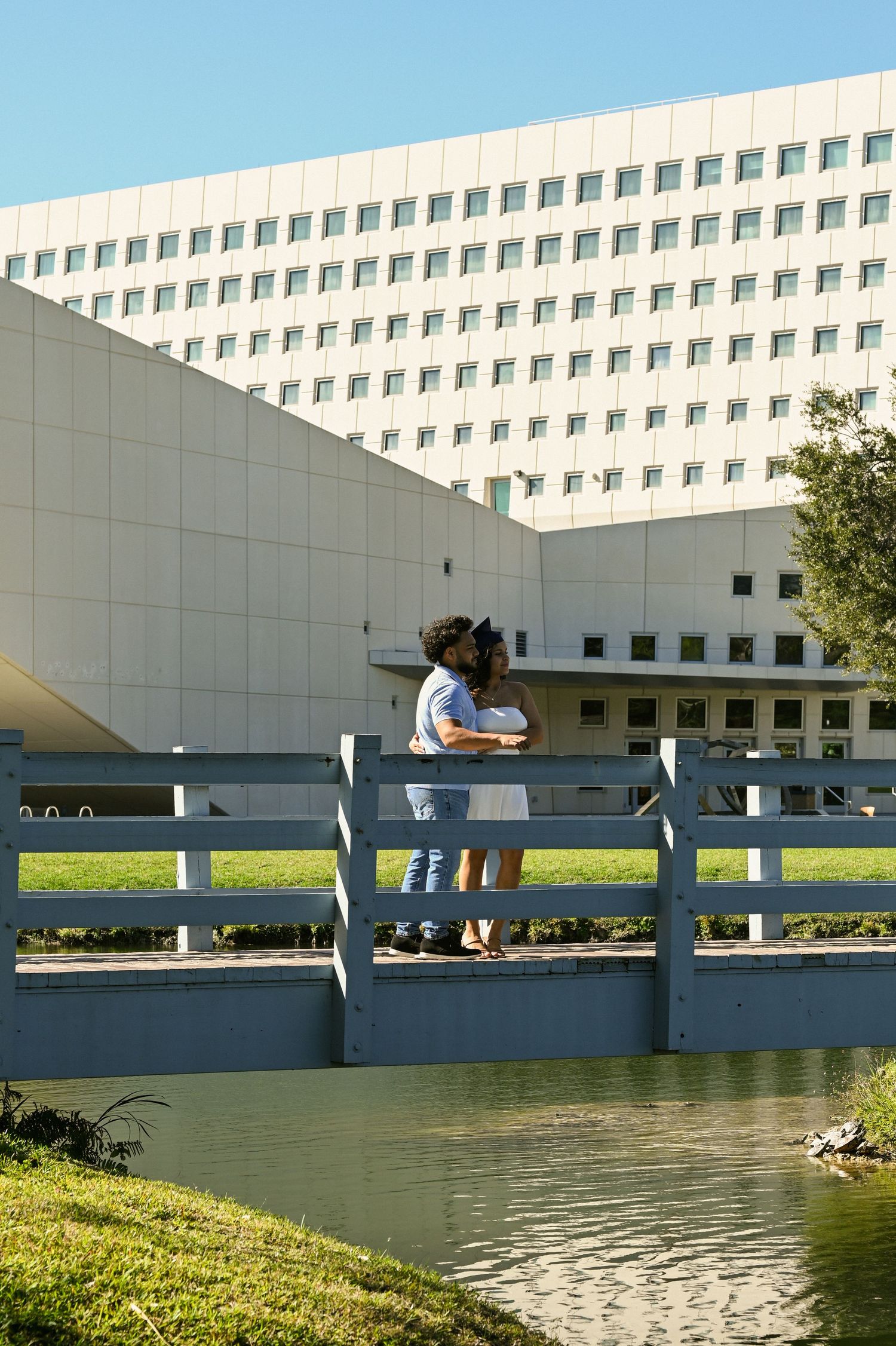 Modern white building with reflective pool and landscaping on a university campus.