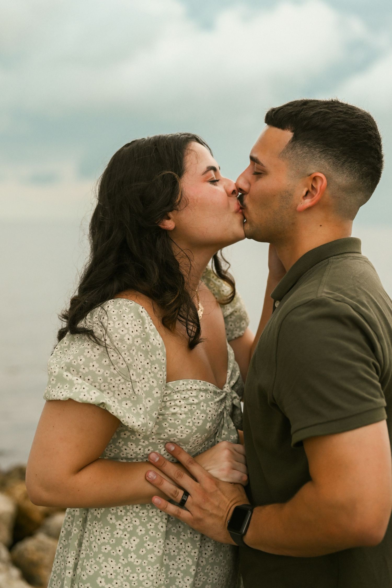 A tender moment between a couple sharing kisses during their coastal photoshoot.