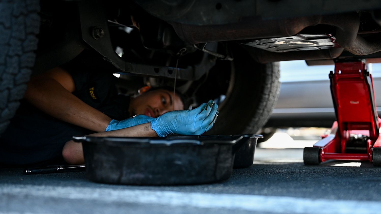 Close-up view of mechanic inspecting underneath a vehicle.