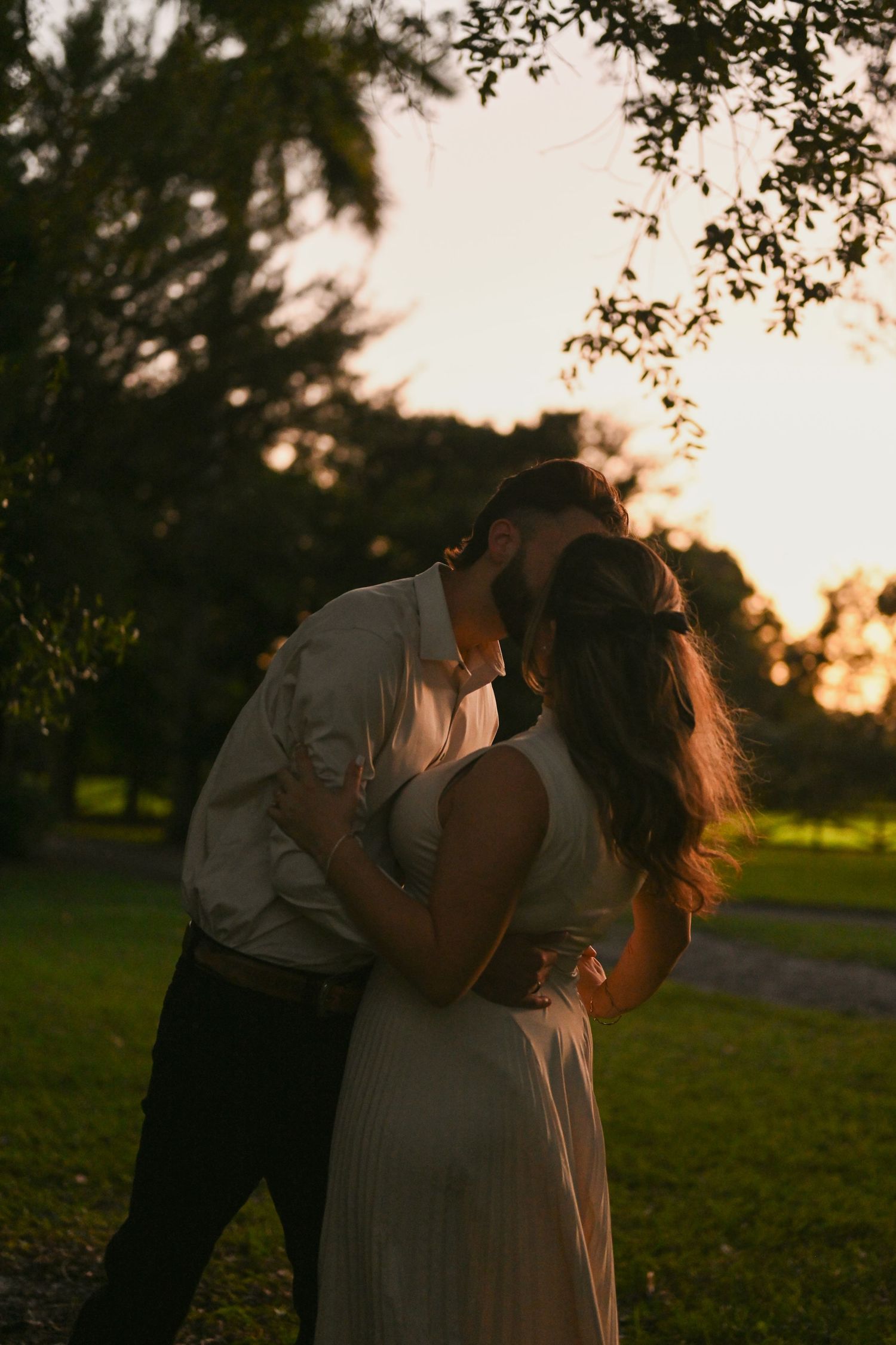 Romantic dance moves in park setting with sunset backdrop.