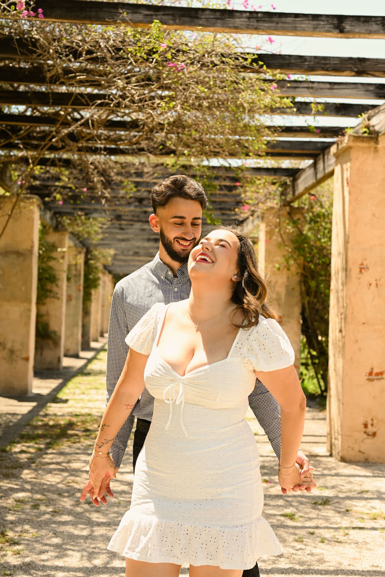 Joyful couple shares genuine laughter during outdoor photo session.