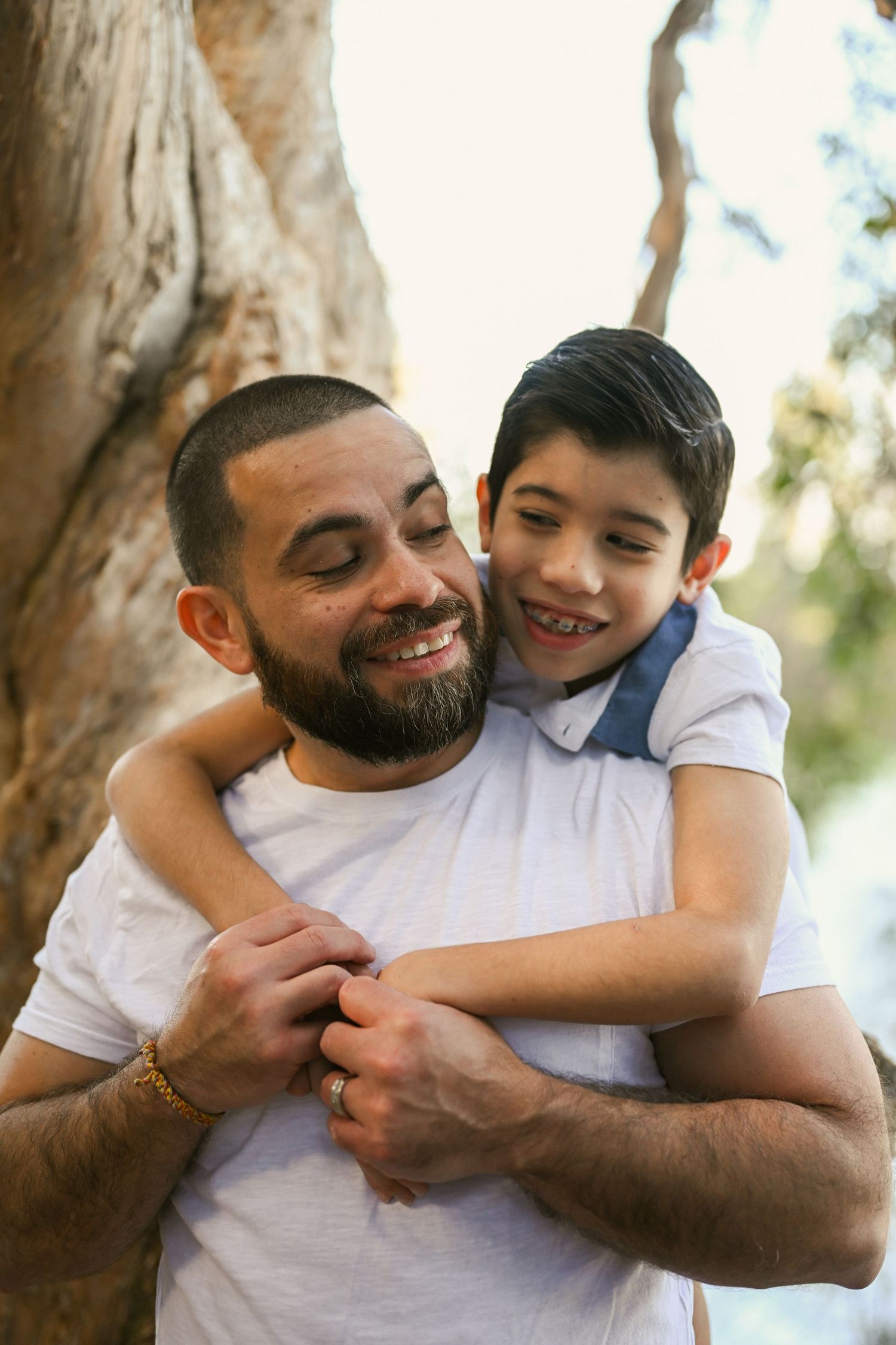 A heartwarming series of candid moments between a father and son embracing and laughing together outdoors.