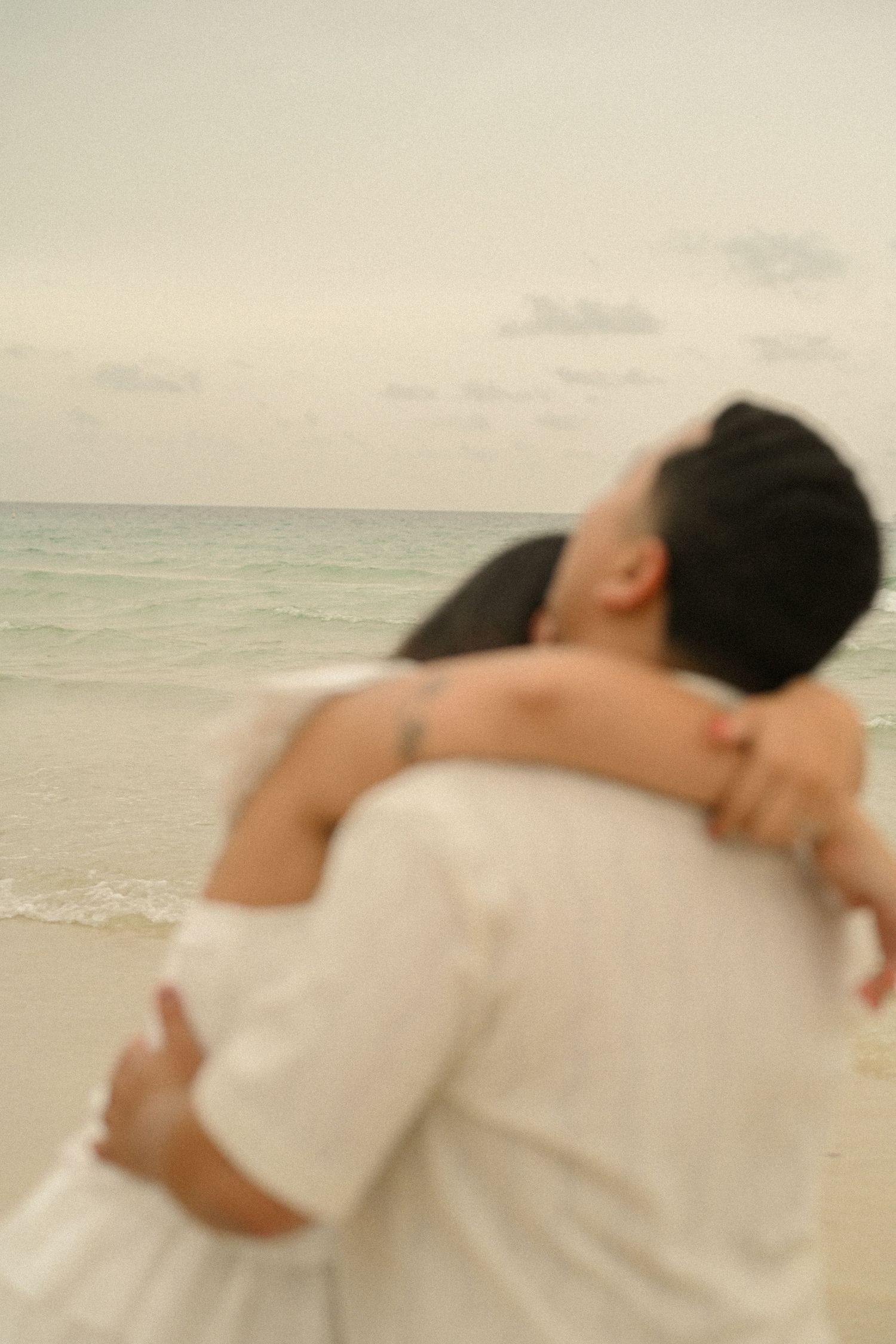 A romantic couple embraces on a serene beach during sunset, creating a dreamy silhouette against the ocean backdrop.