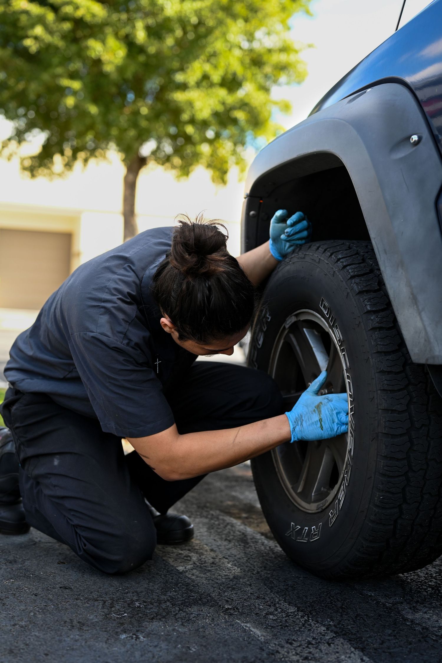 Mechanic inspecting car tire and wheel assembly during service.