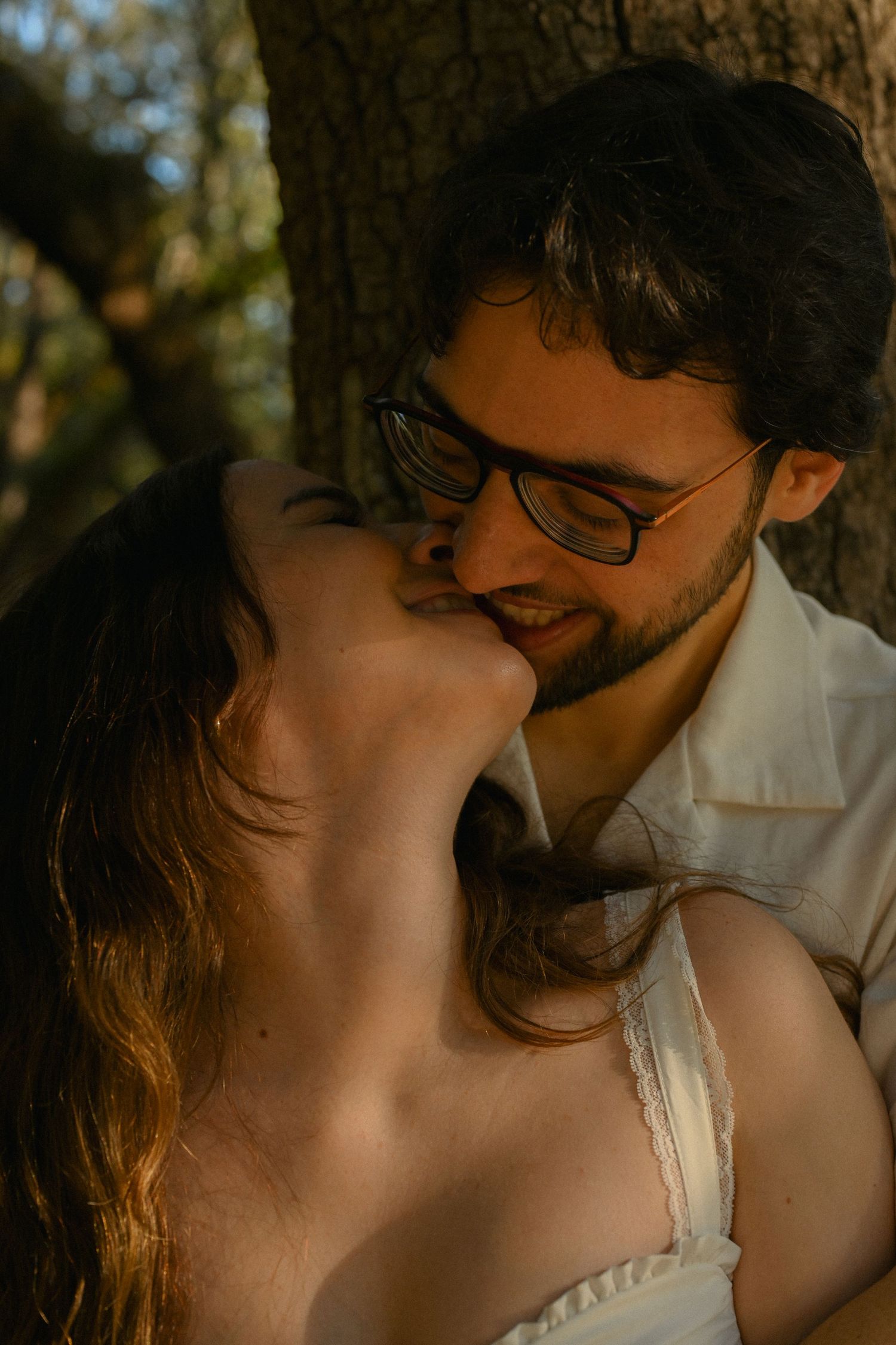 Romantic couple sharing an intimate moment in warm sunlight against a natural outdoor background.