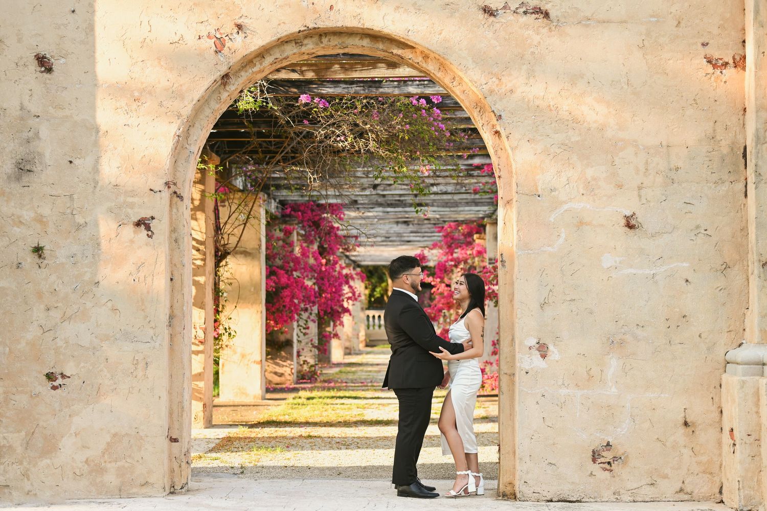 Stone archways with pink bougainvillea flowers creating romantic outdoor setting.