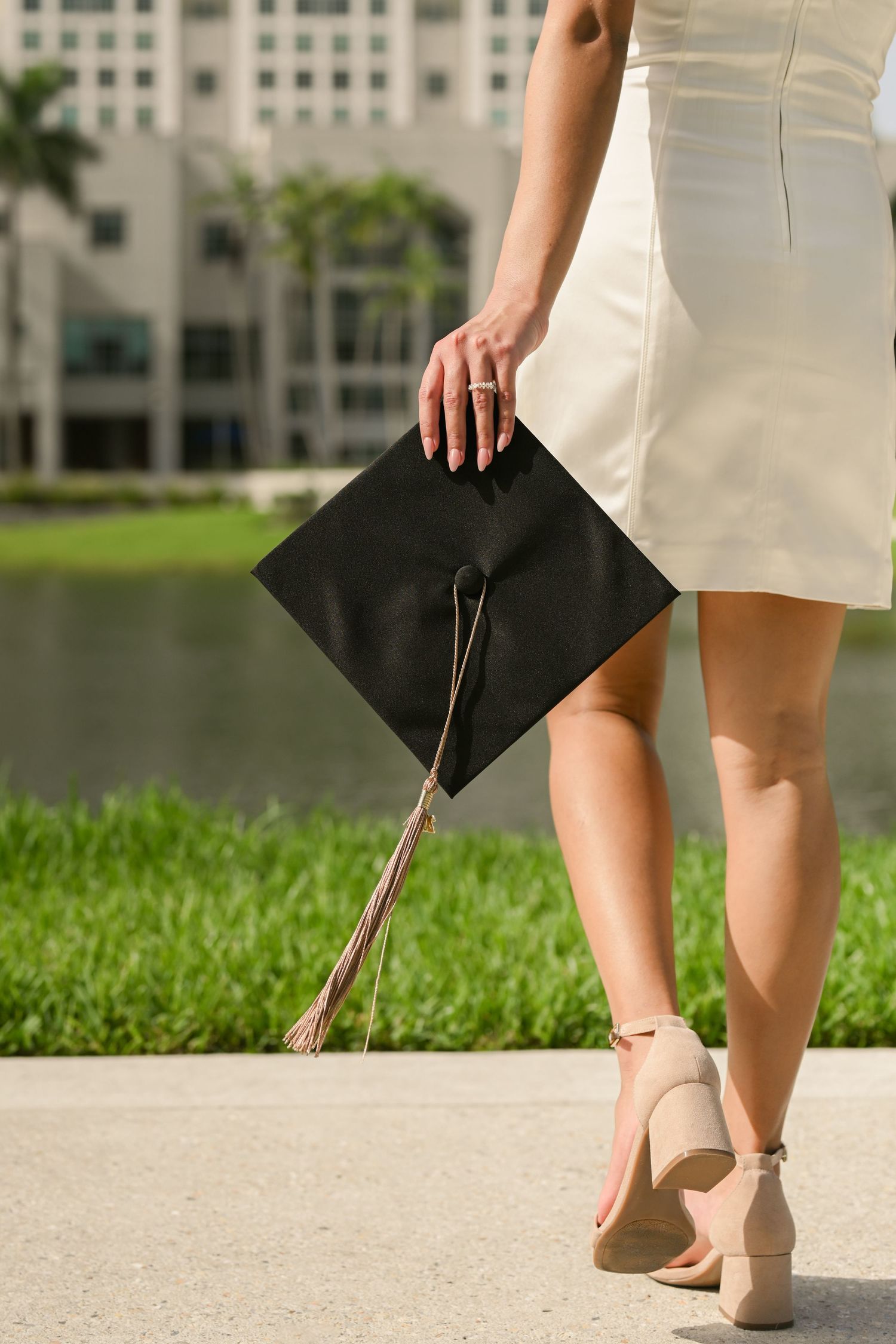 Close-up of graduation cap and heels during outdoor campus photoshoot.