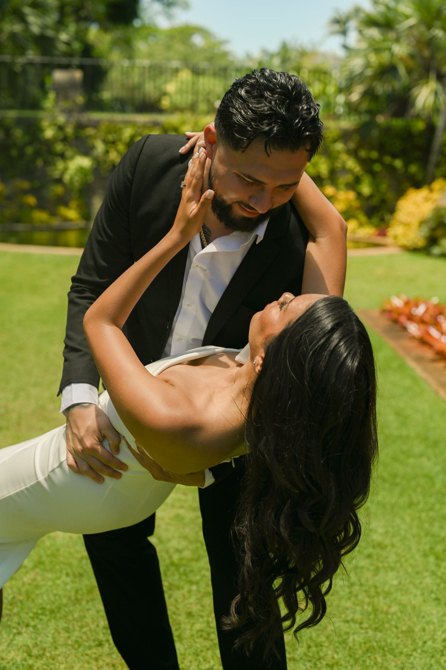 A romantic dip pose captured in a beautiful garden setting with vibrant greenery.