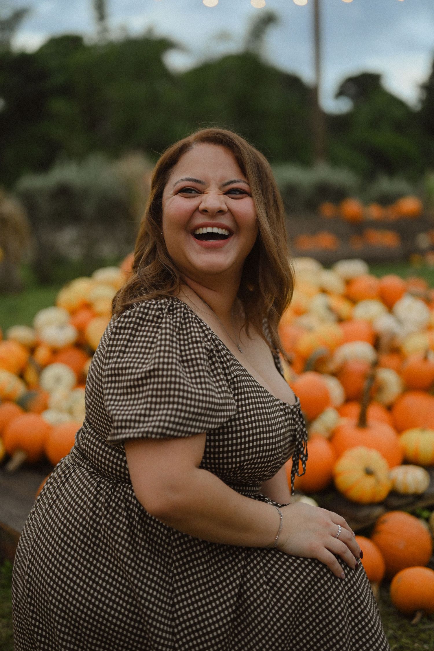 A gingham dress worn at a festive pumpkin patch with twinkling lights in the background.