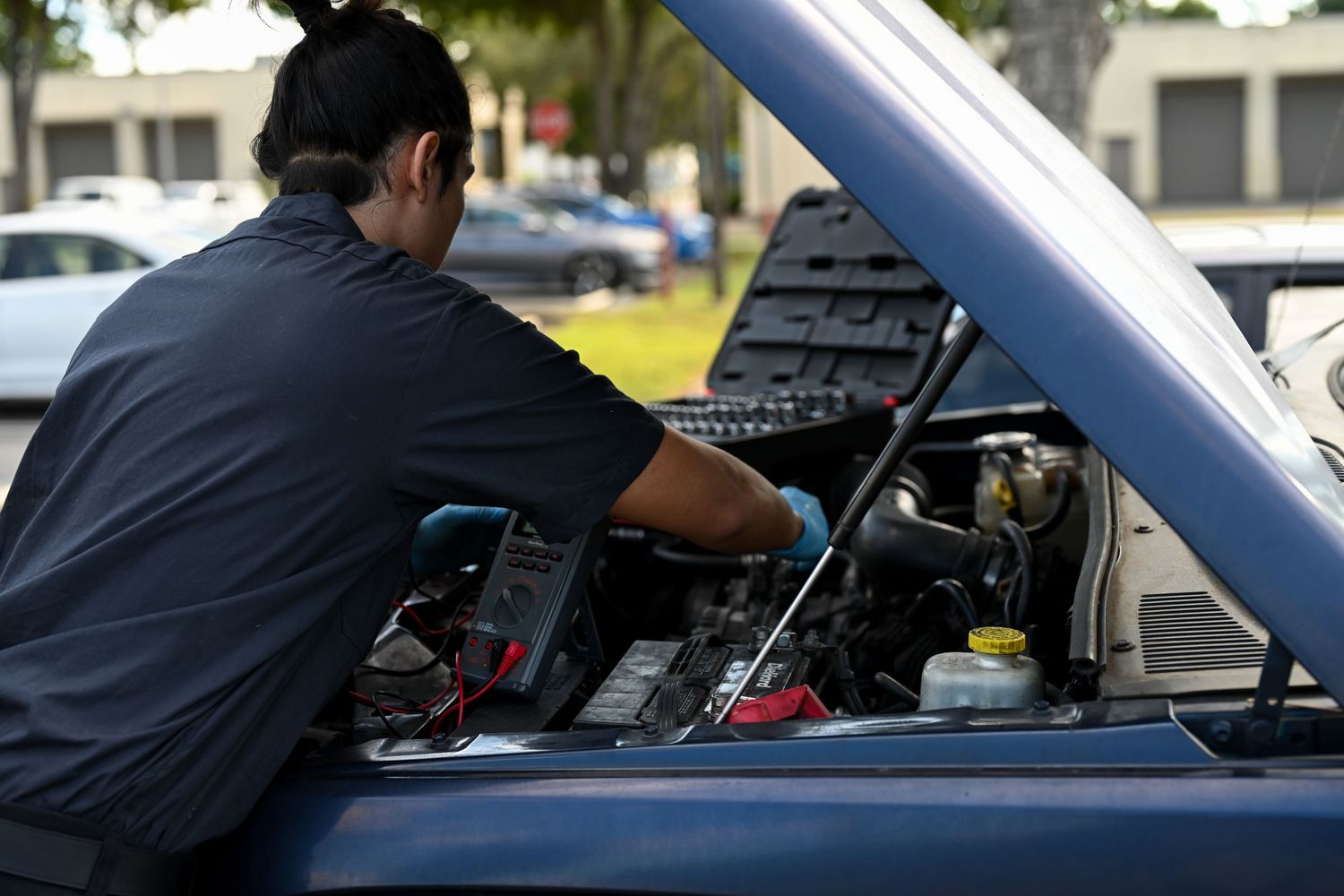 Automotive professional conducting engine diagnostics with testing equipment.
