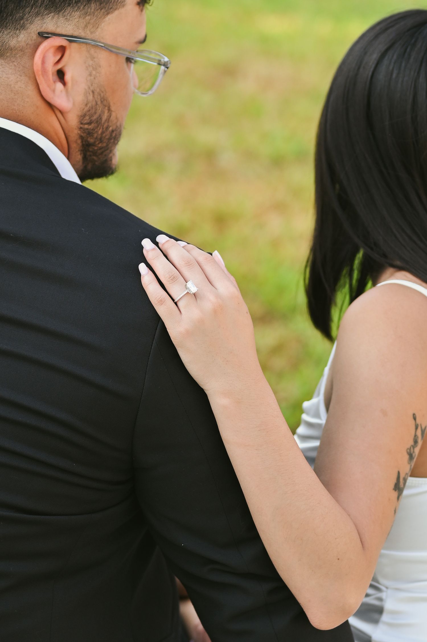 Close-up shots of couple embracing on stone bench with woman showing engagement ring.