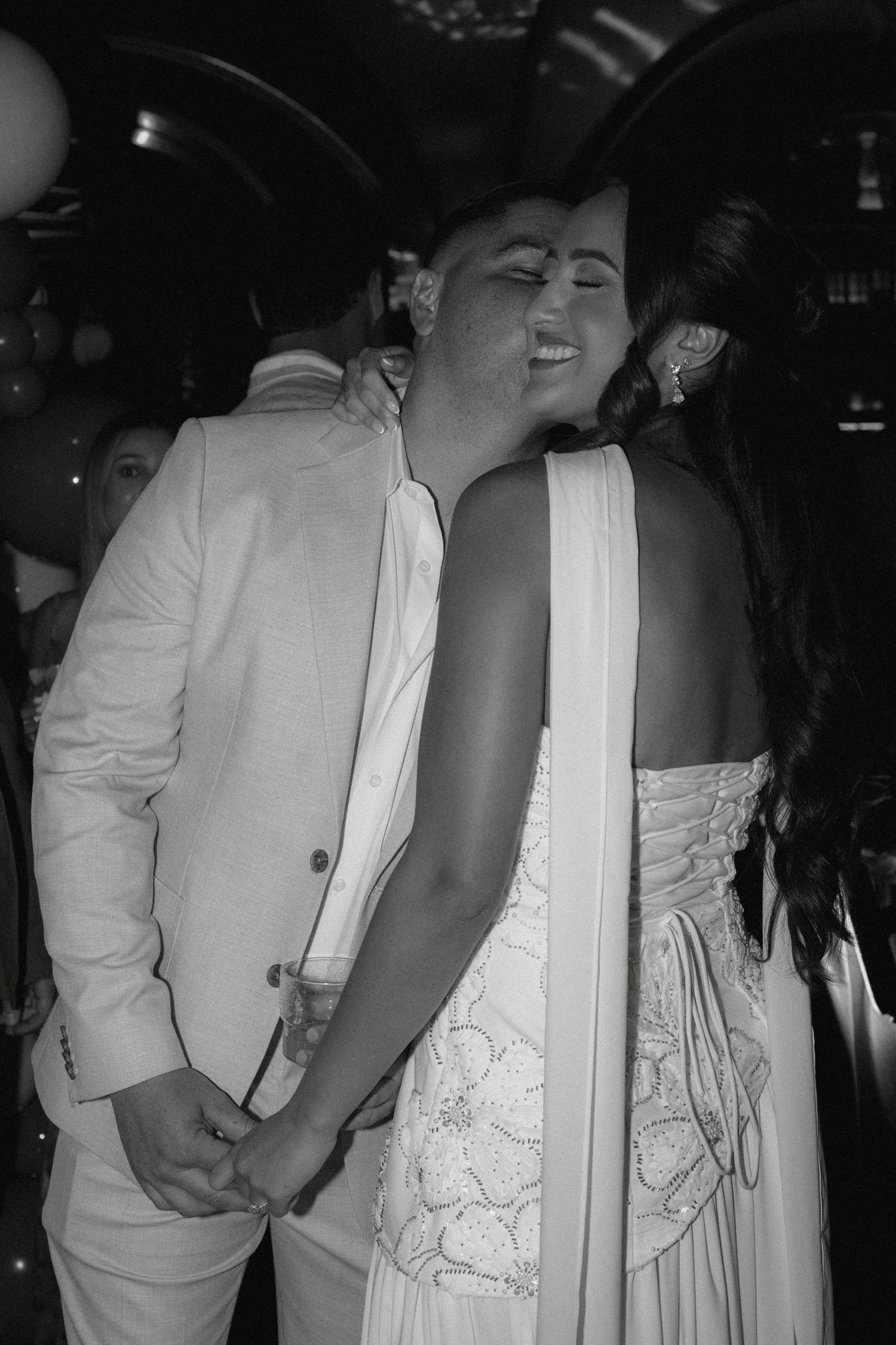 Couple sharing a tender embrace on the dance floor at a wedding reception in black and white.