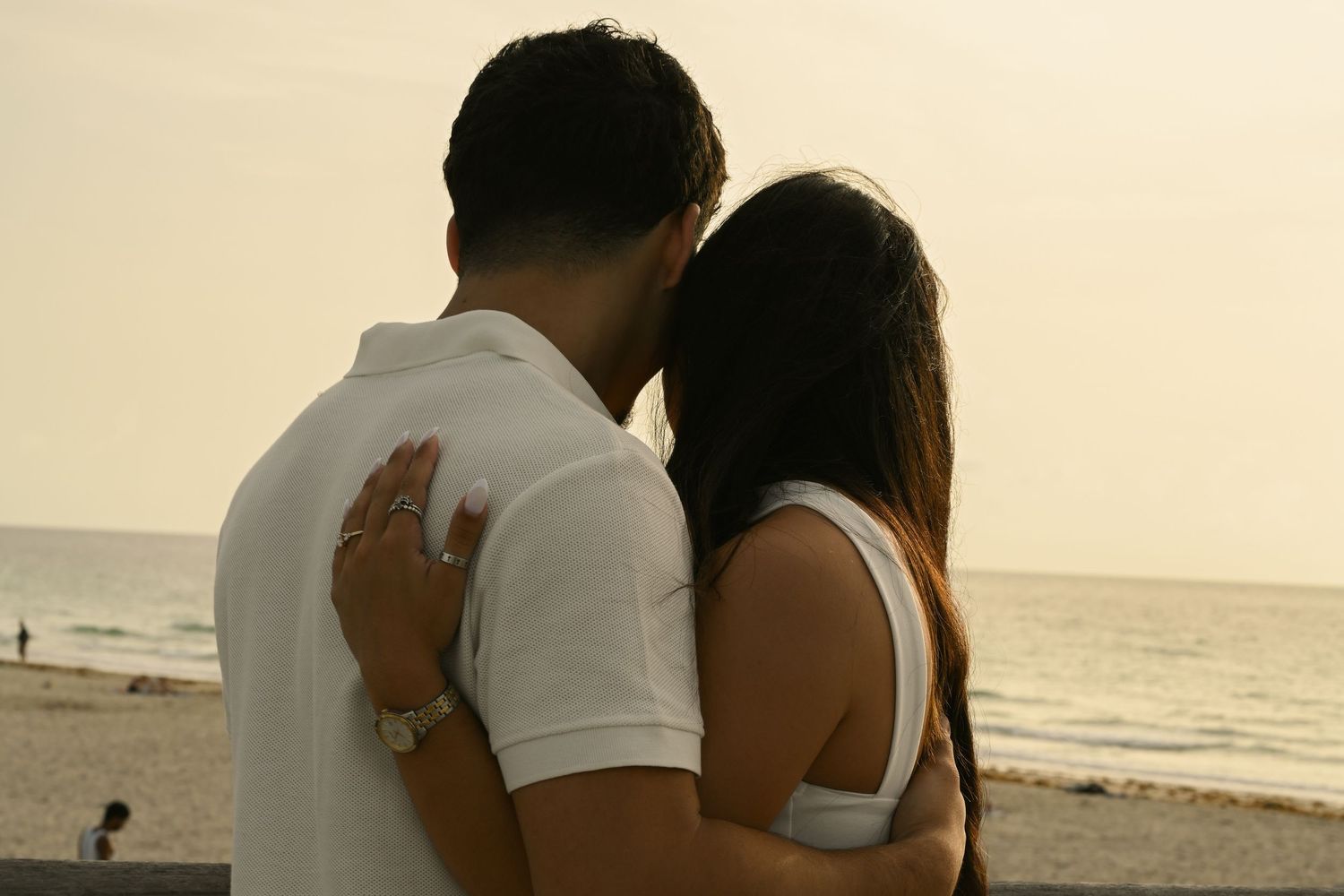 Silhouetted couple embracing on beach during sunset.