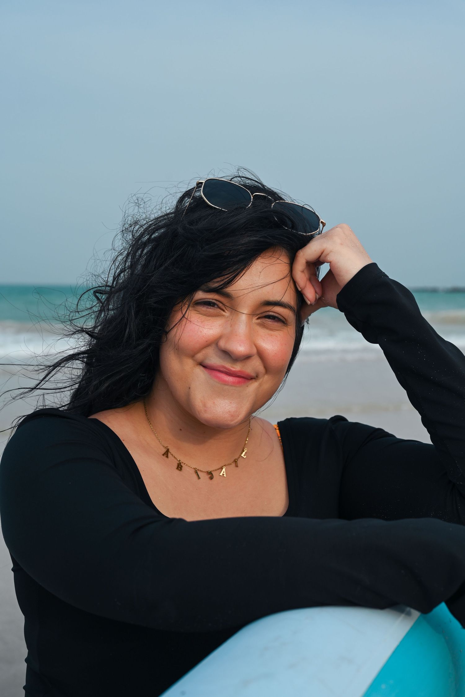 Casual beachside portrait series with surfboard and ocean backdrop.