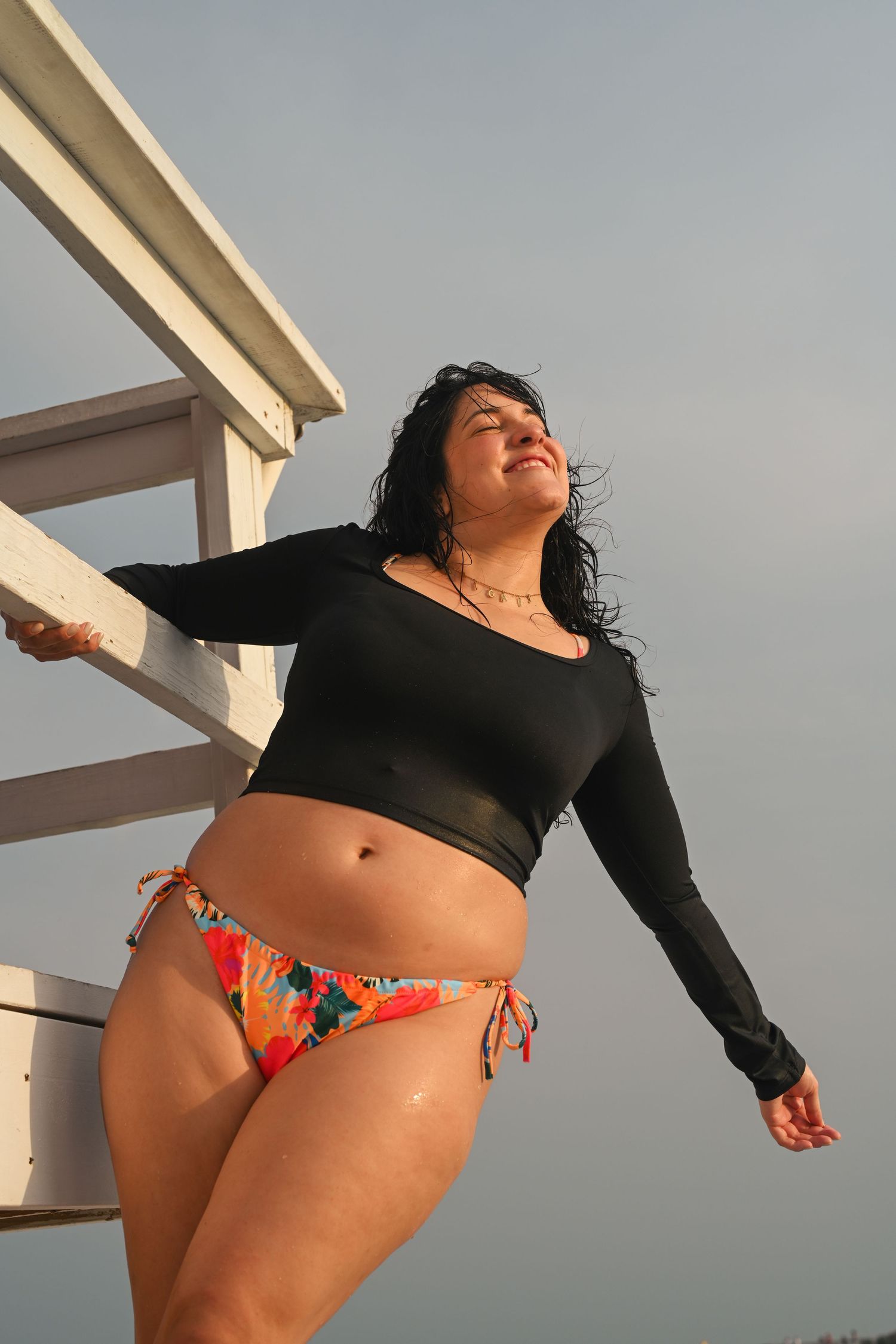 Figure in black top and colorful swimwear poses outdoors.