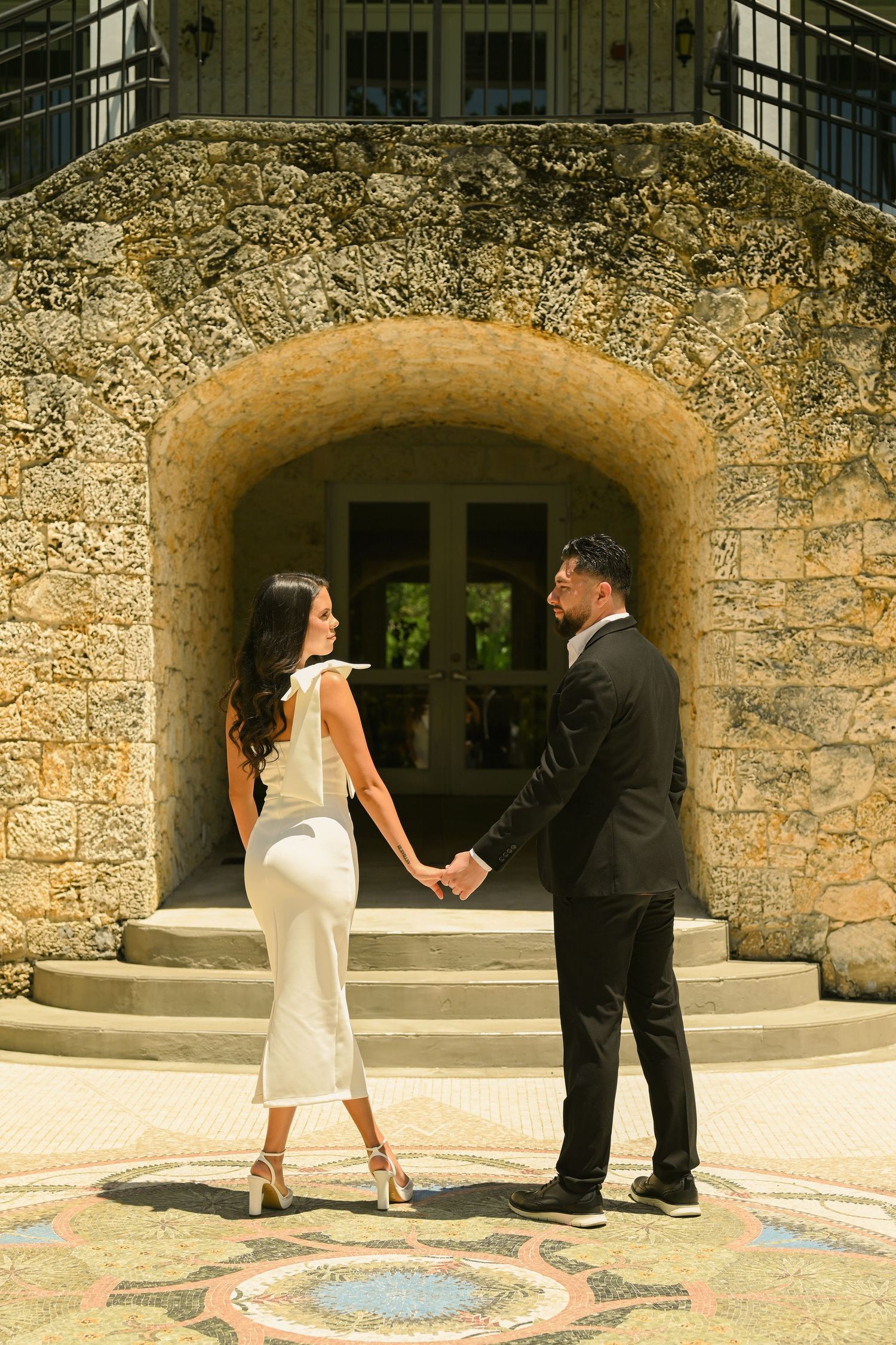A series of photos showing a couple's playful interaction near a decorative stone wall.