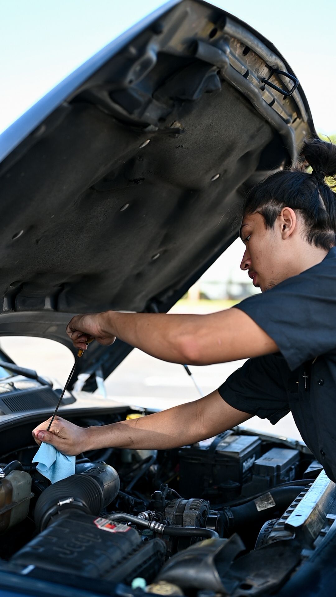 Mechanic reaching into engine compartment during vehicle service.