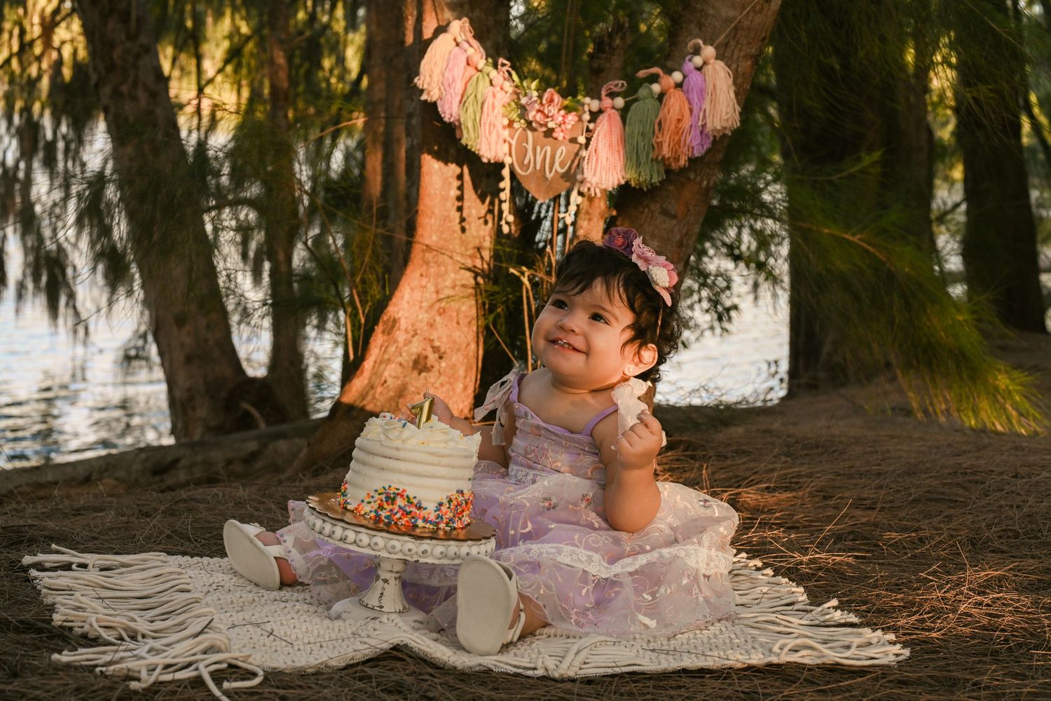 Outdoor cake smash photography session with pink decorations and white cake.