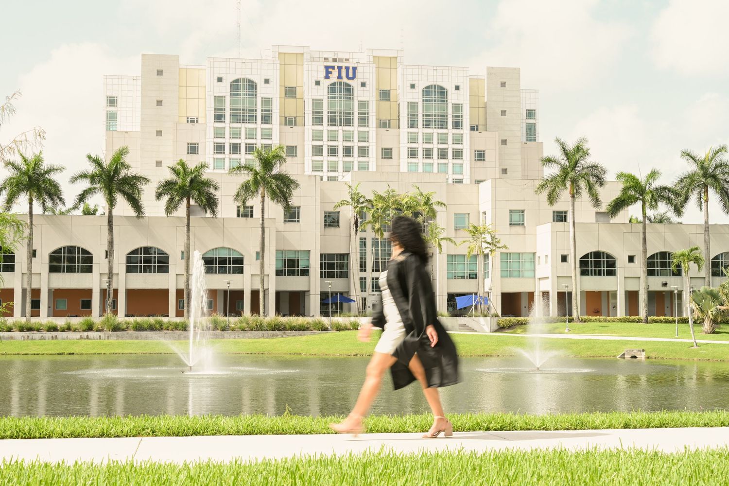 Wide panoramic view of university campus with lake, palm trees and modern architecture.