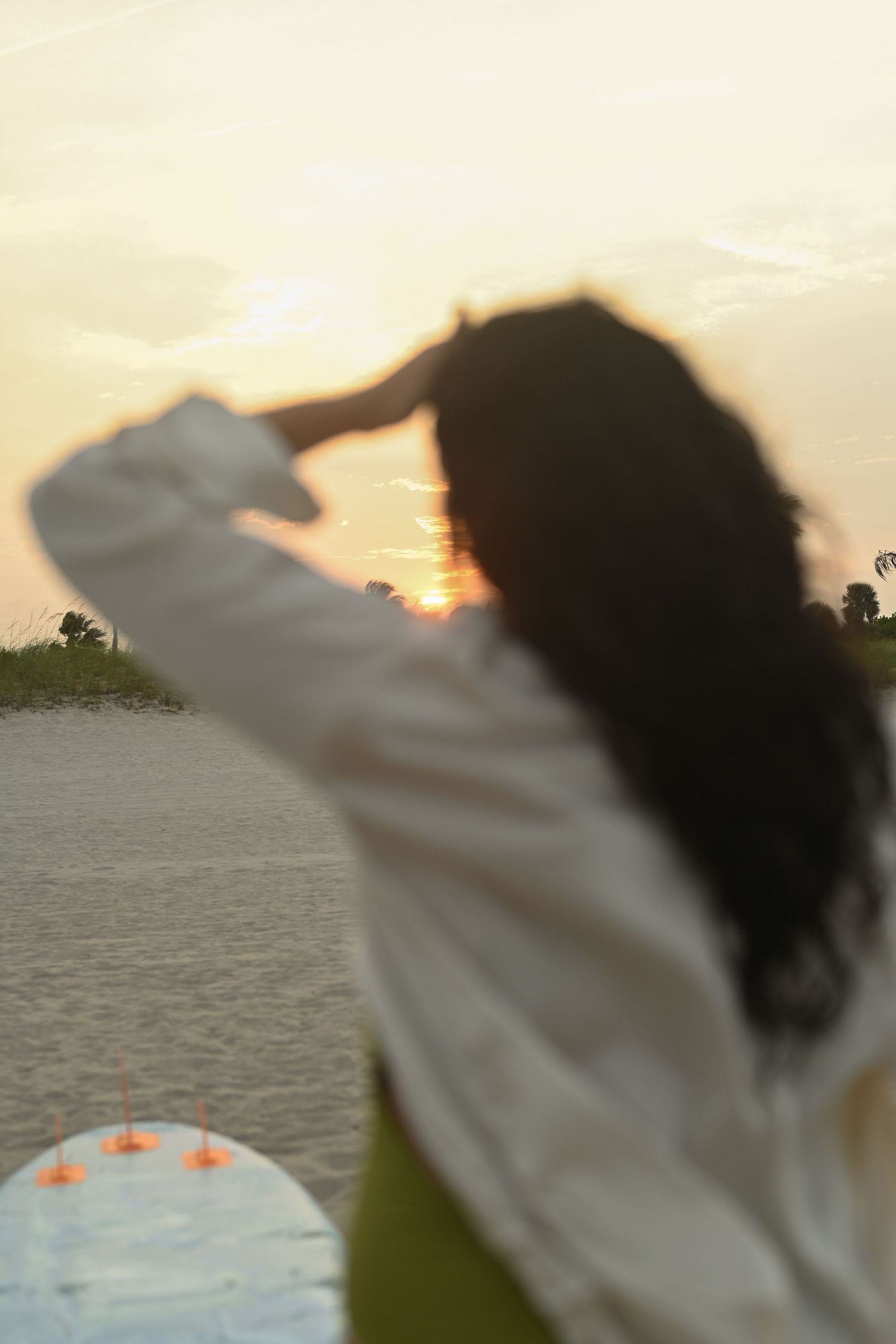 Silhouette reaching toward the setting sun over water.