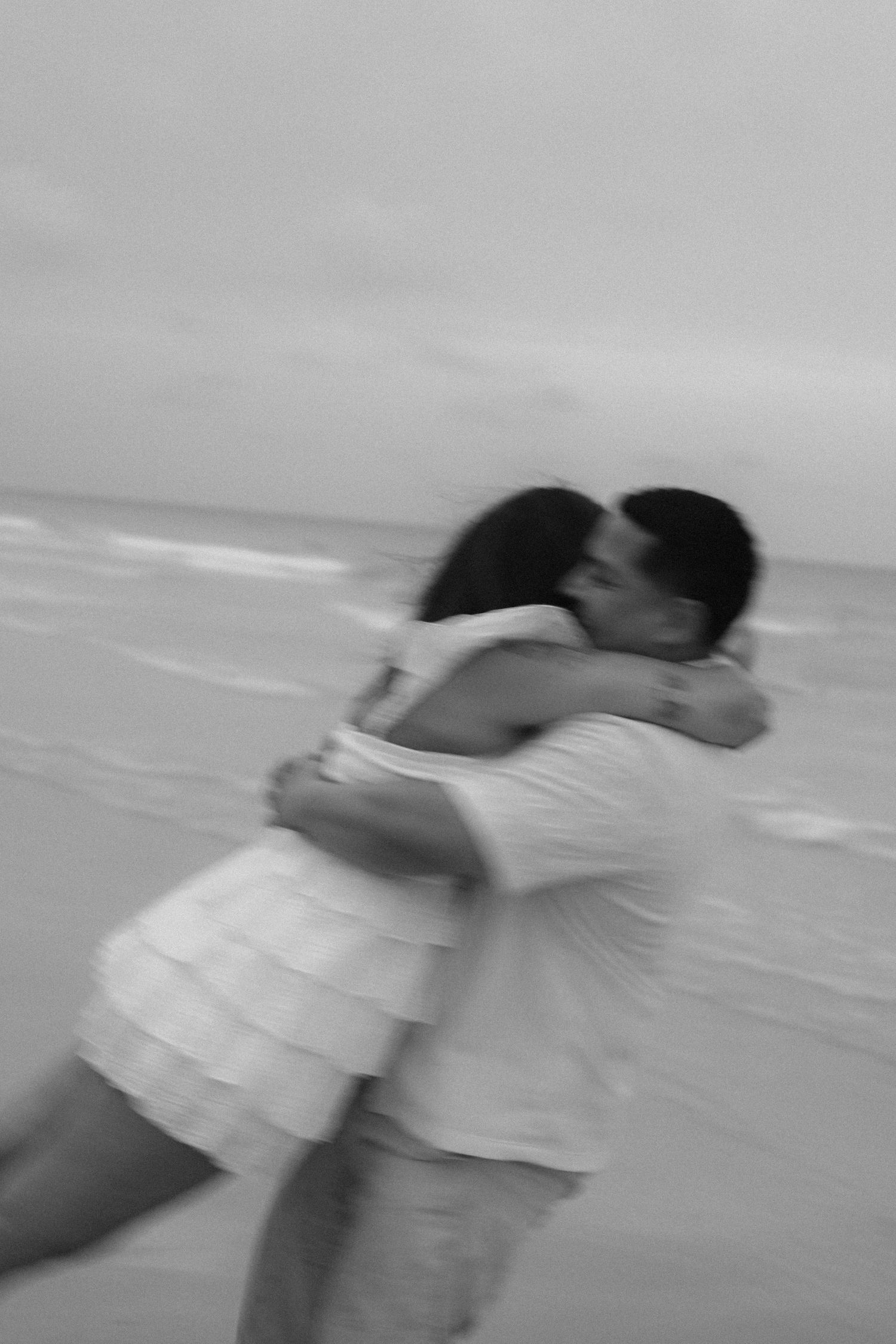 Artistic motion shots of a couple embracing and spinning on the shoreline.