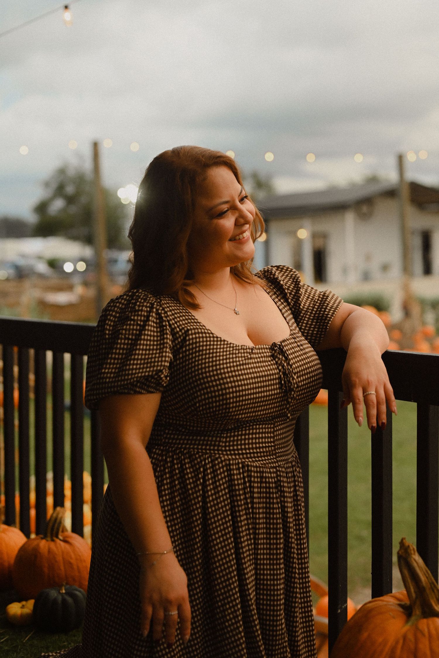 A brown polka dot dress against a backdrop of pumpkins and wooden railings during golden hour.