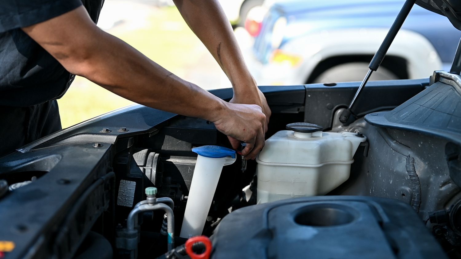 Technician performing routine maintenance on vehicle engine.