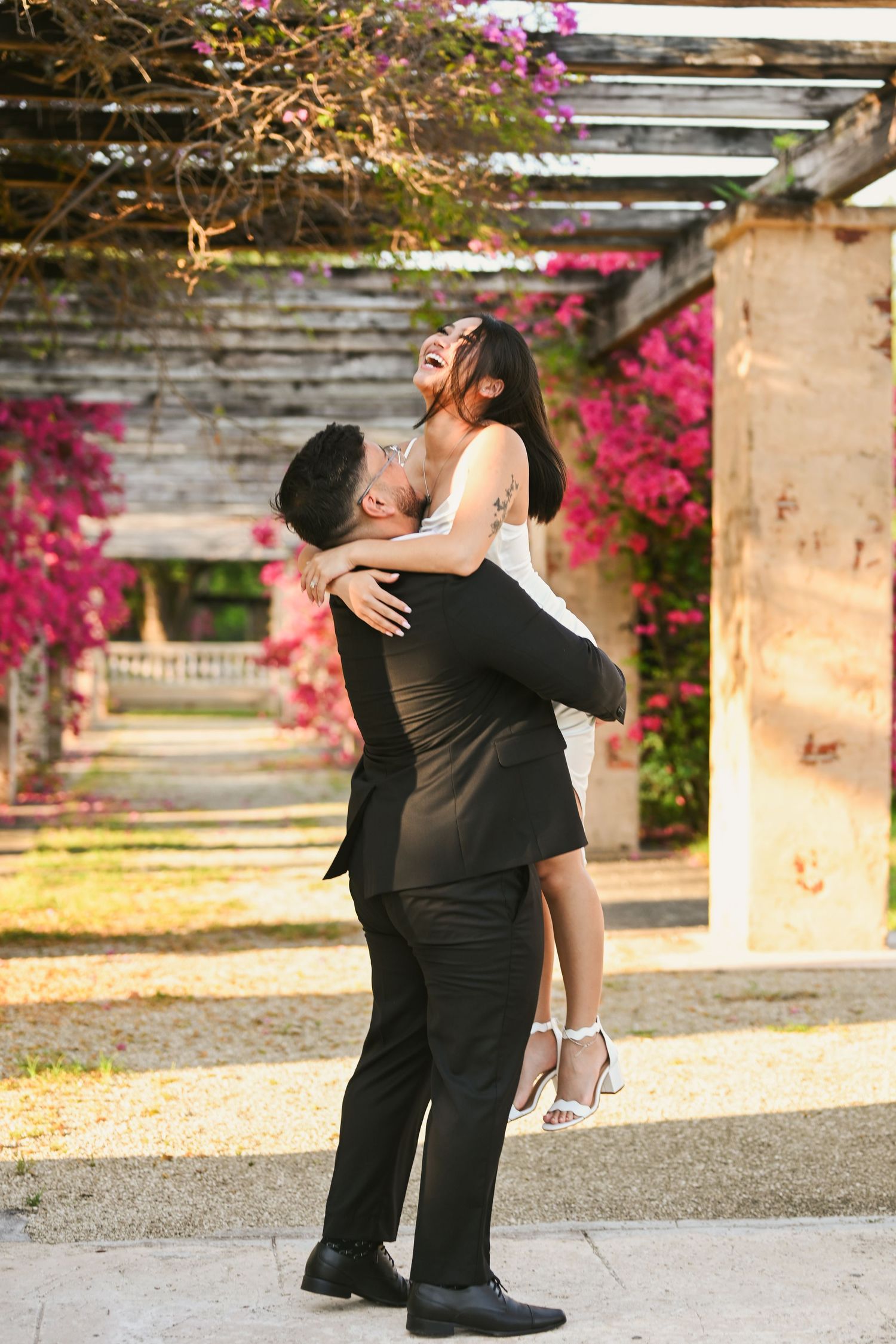 Romantic dance poses captured under stone archways with pink flowers.