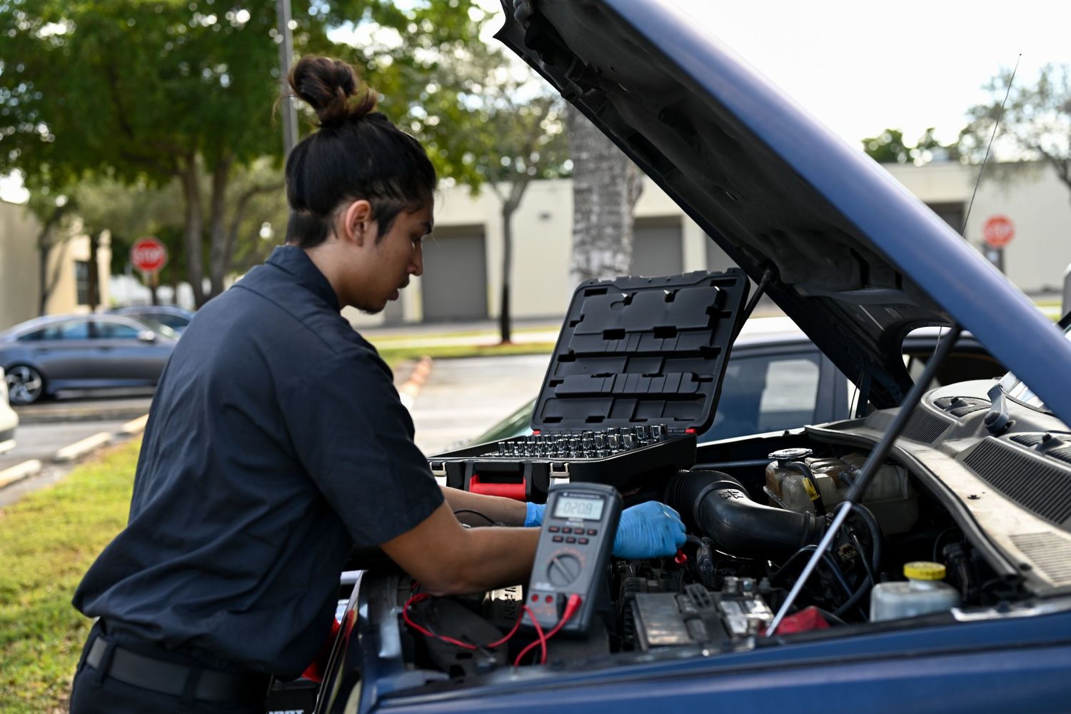 Service technician using diagnostic tools to inspect car engine components.