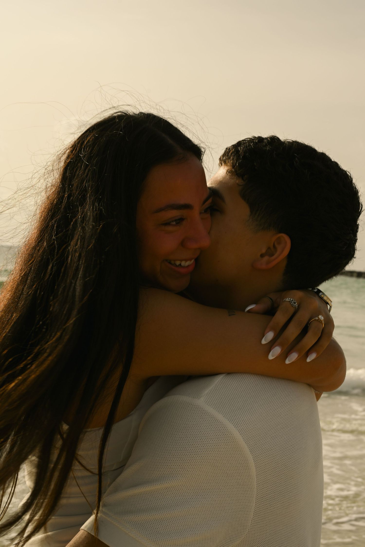 An intimate moment between a couple sharing a close embrace on the beach.