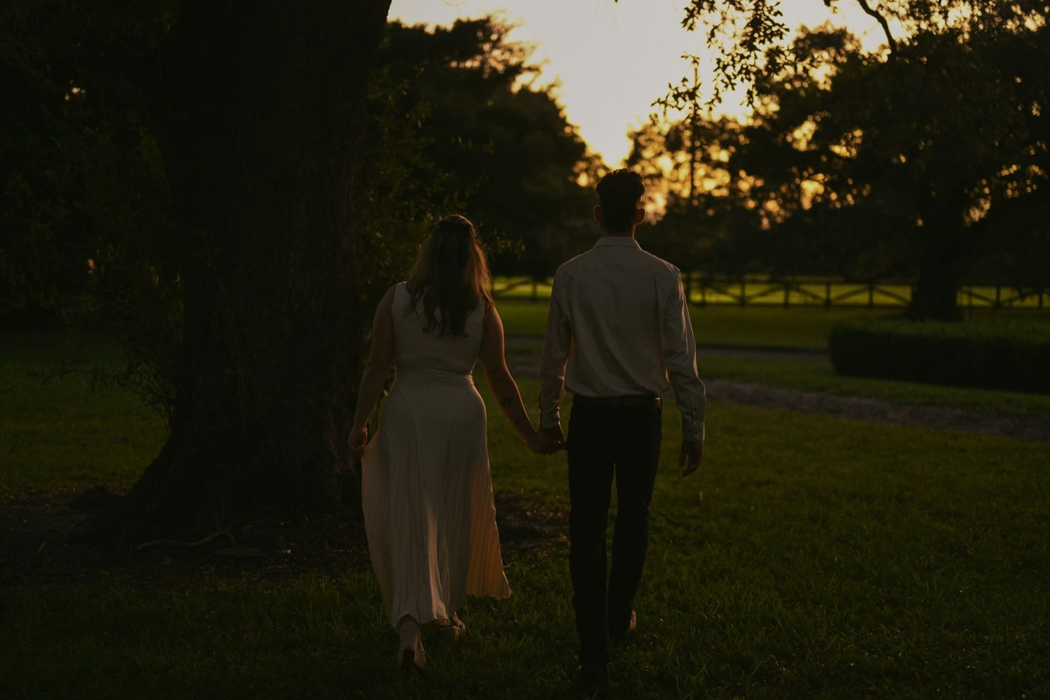 Silhouettes walking together in park during sunset.