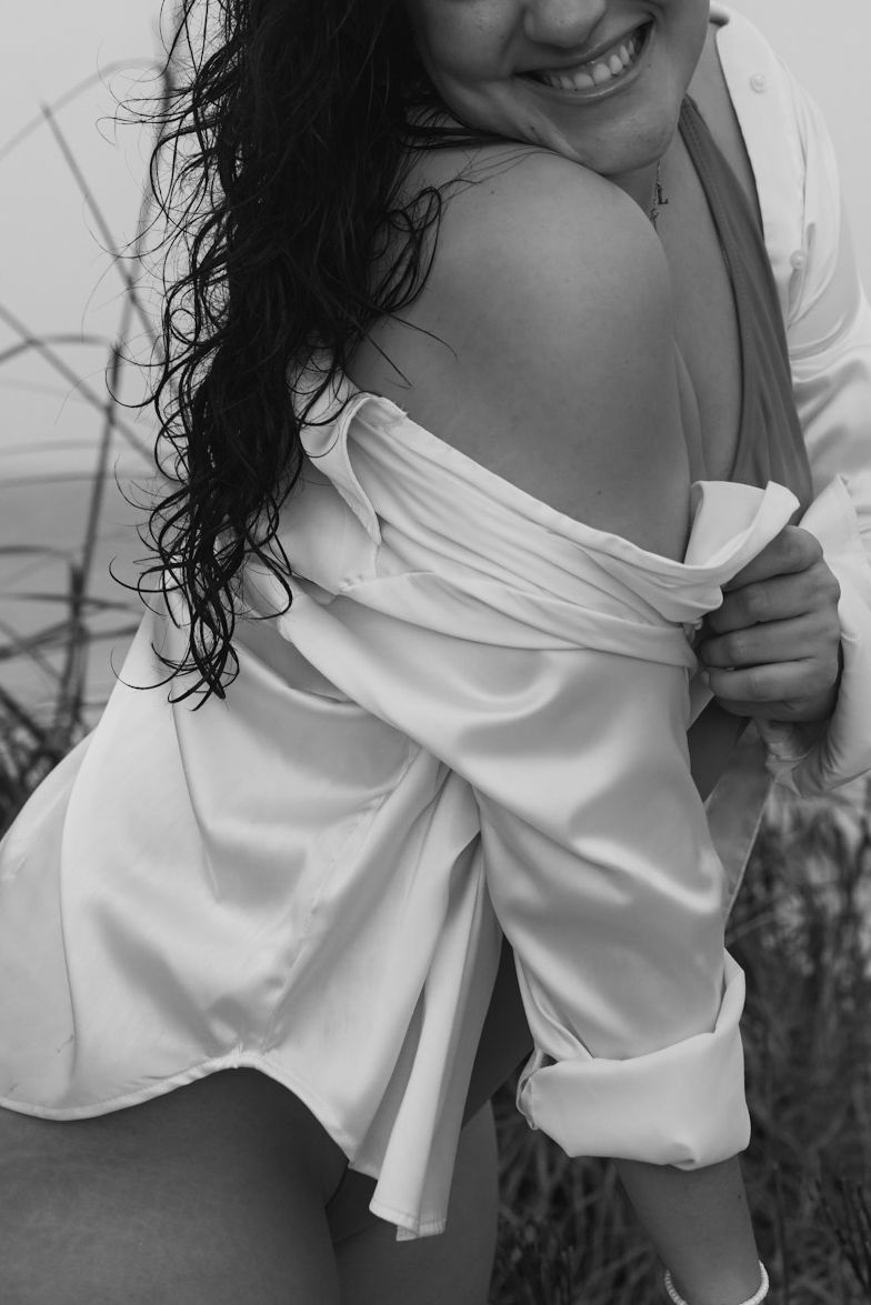 Figure in white flowing top poses against neutral background.
