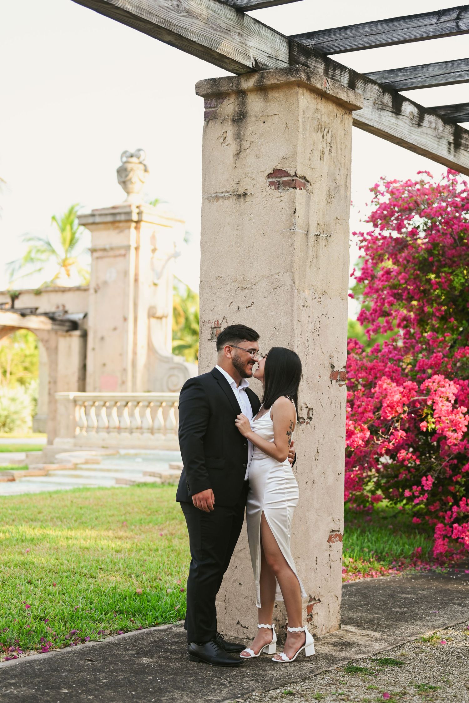 Romantic photoshoot under a pergola surrounded by blooming pink bougainvillea flowers.
