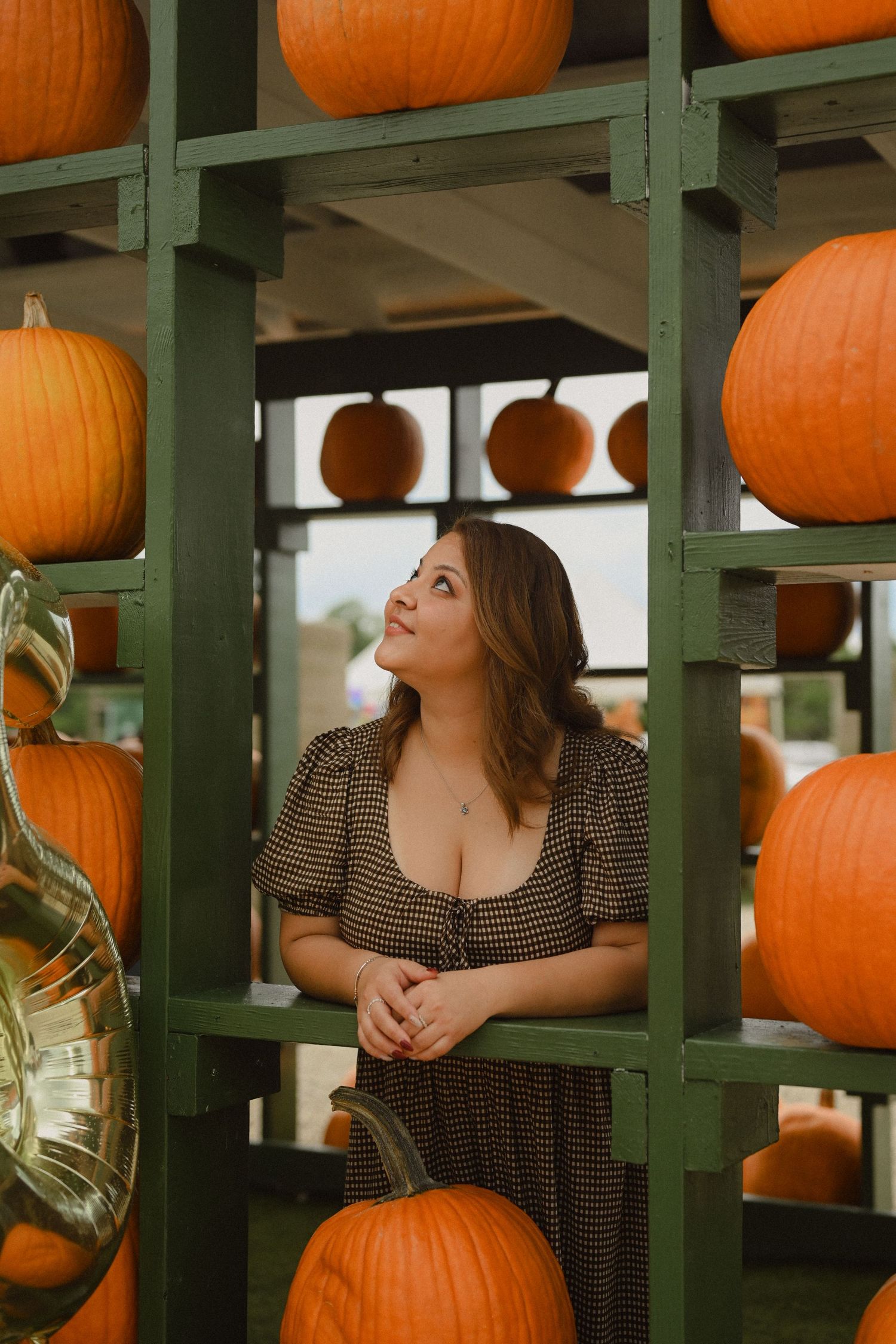 Orange pumpkins arranged on green wooden shelves in a rustic fall display.