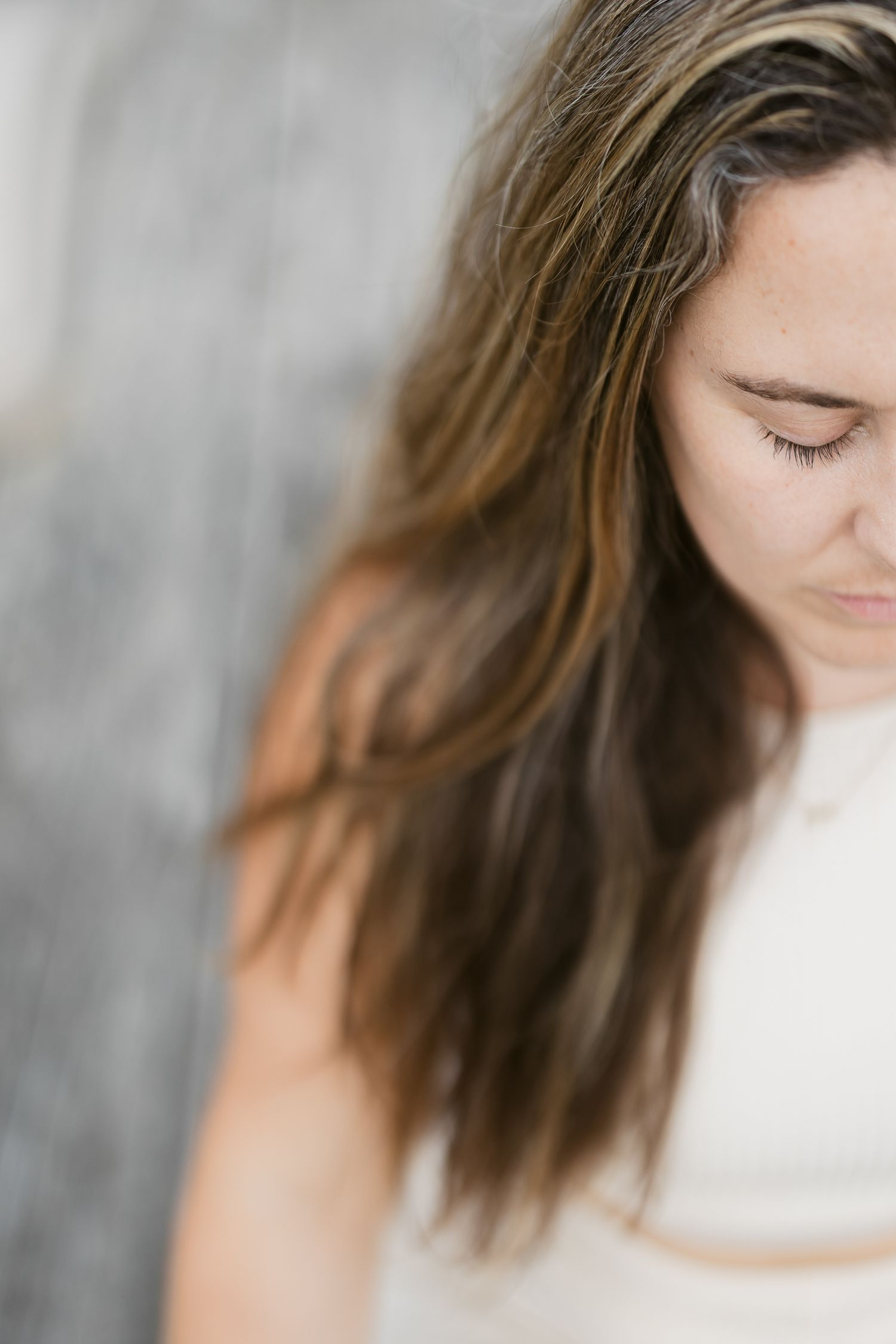 Close-up profile portrait with closed eyes and soft lighting against a light gray background.