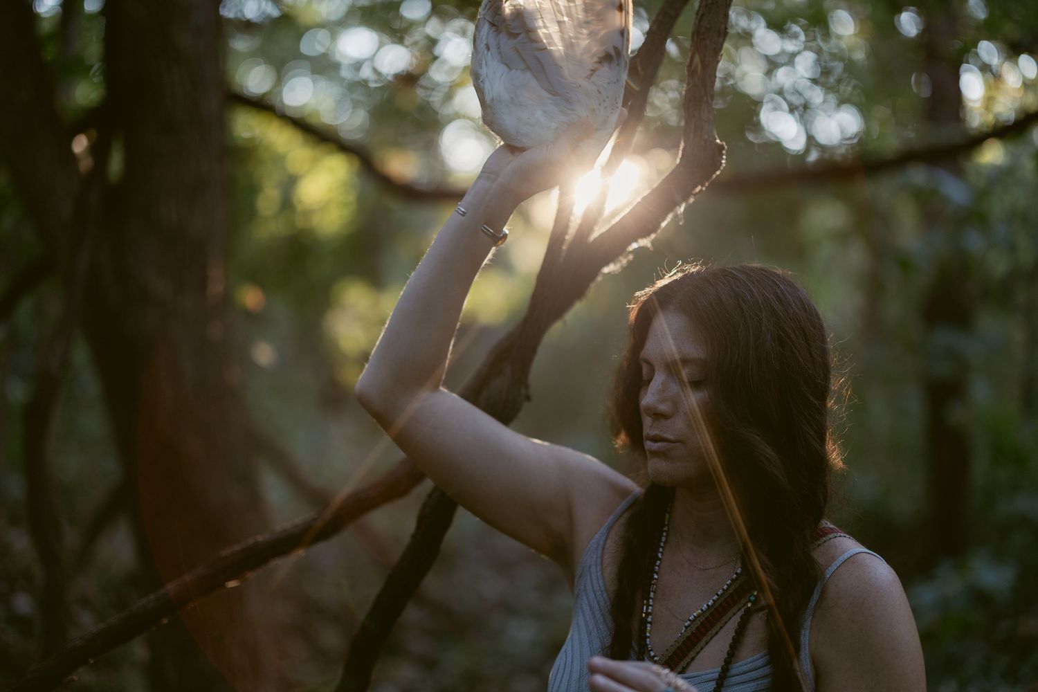 A couple shares an intimate moment in a sunlit forest setting during a romantic outdoor photoshoot.
