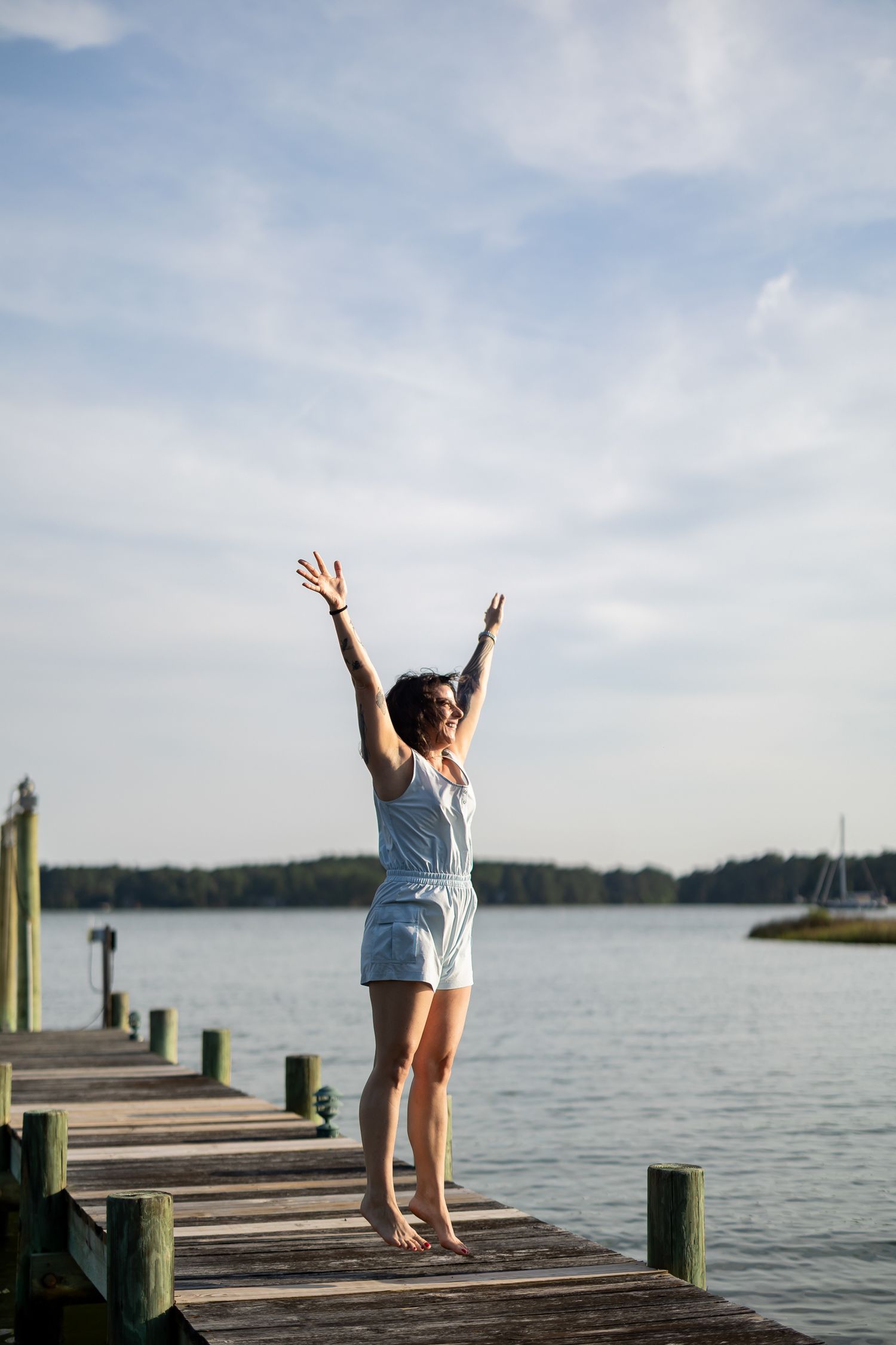 Group of photos showing woman on wooden dock by lake, raising arms joyfully against cloudy sky and water view.