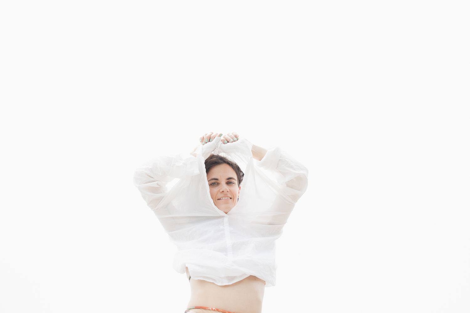 Person in a white chef jacket sitting against a bright background posing confidently.