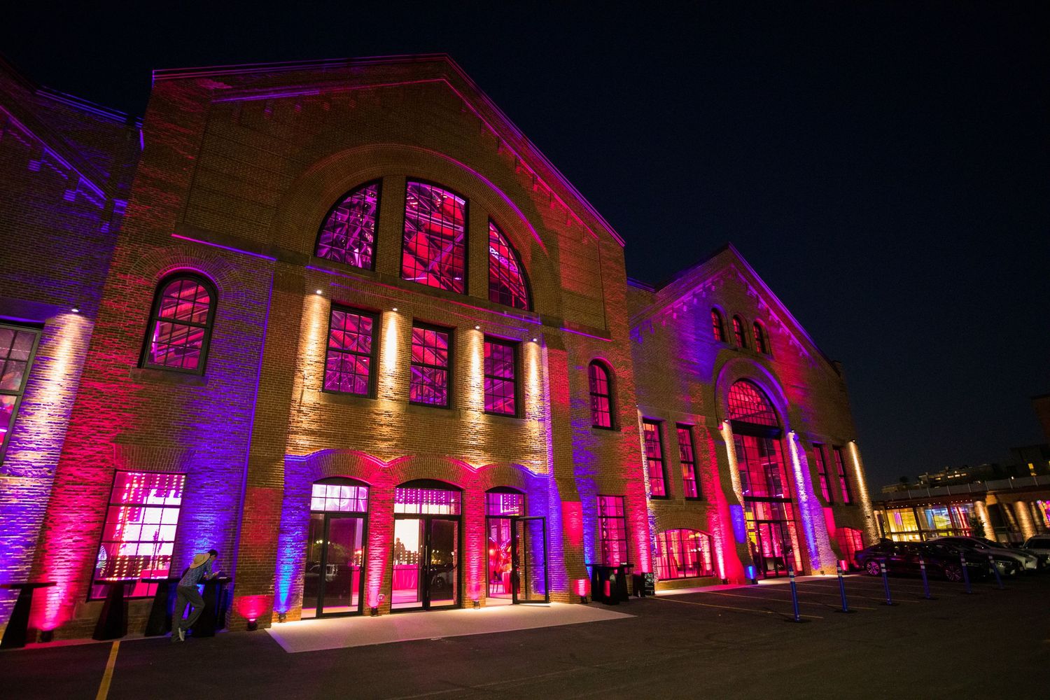 Historic building illuminated with dramatic pink and purple lighting for an evening event.