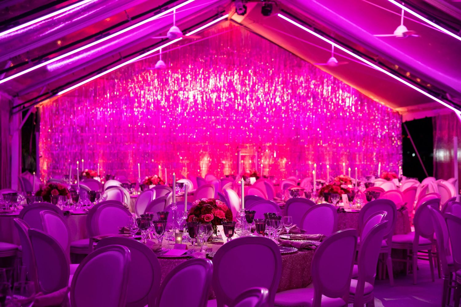 Luxurious event space bathed in magenta lighting with cascading crystal chandelier installations.