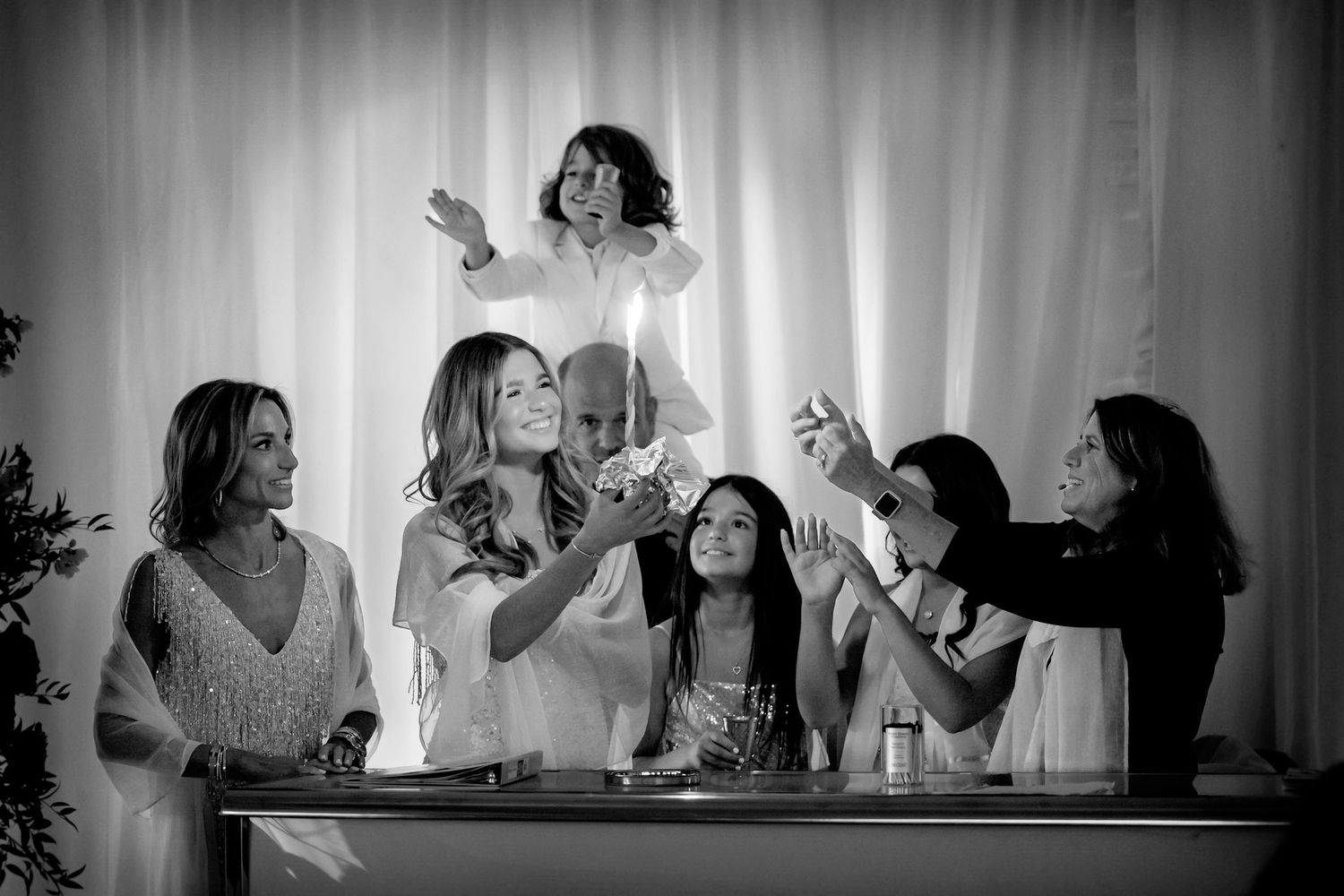 Black and white celebration photo showing party guests raising glasses for a toast.
