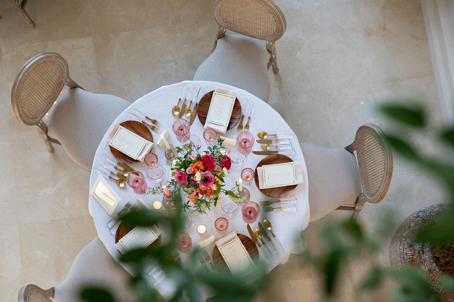 Overhead view of an elegantly set round dining table with floral centerpiece and place settings.
