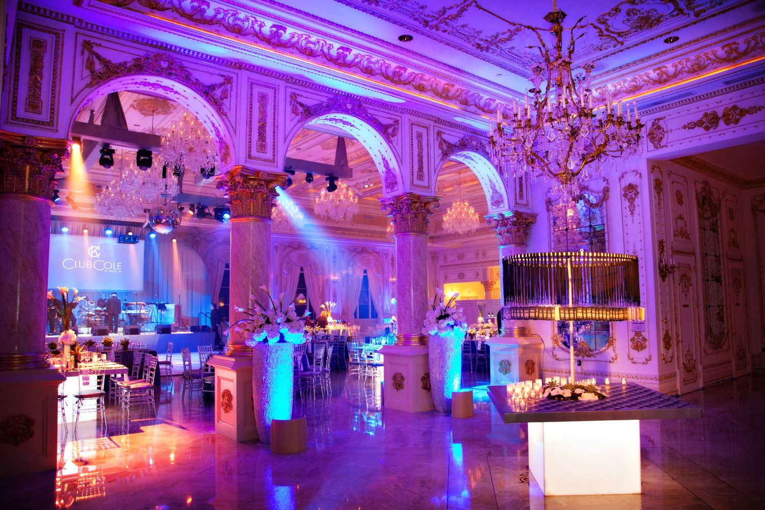 Elegant ballroom venue with ornate architecture illuminated in purple and blue lighting for an upscale event.