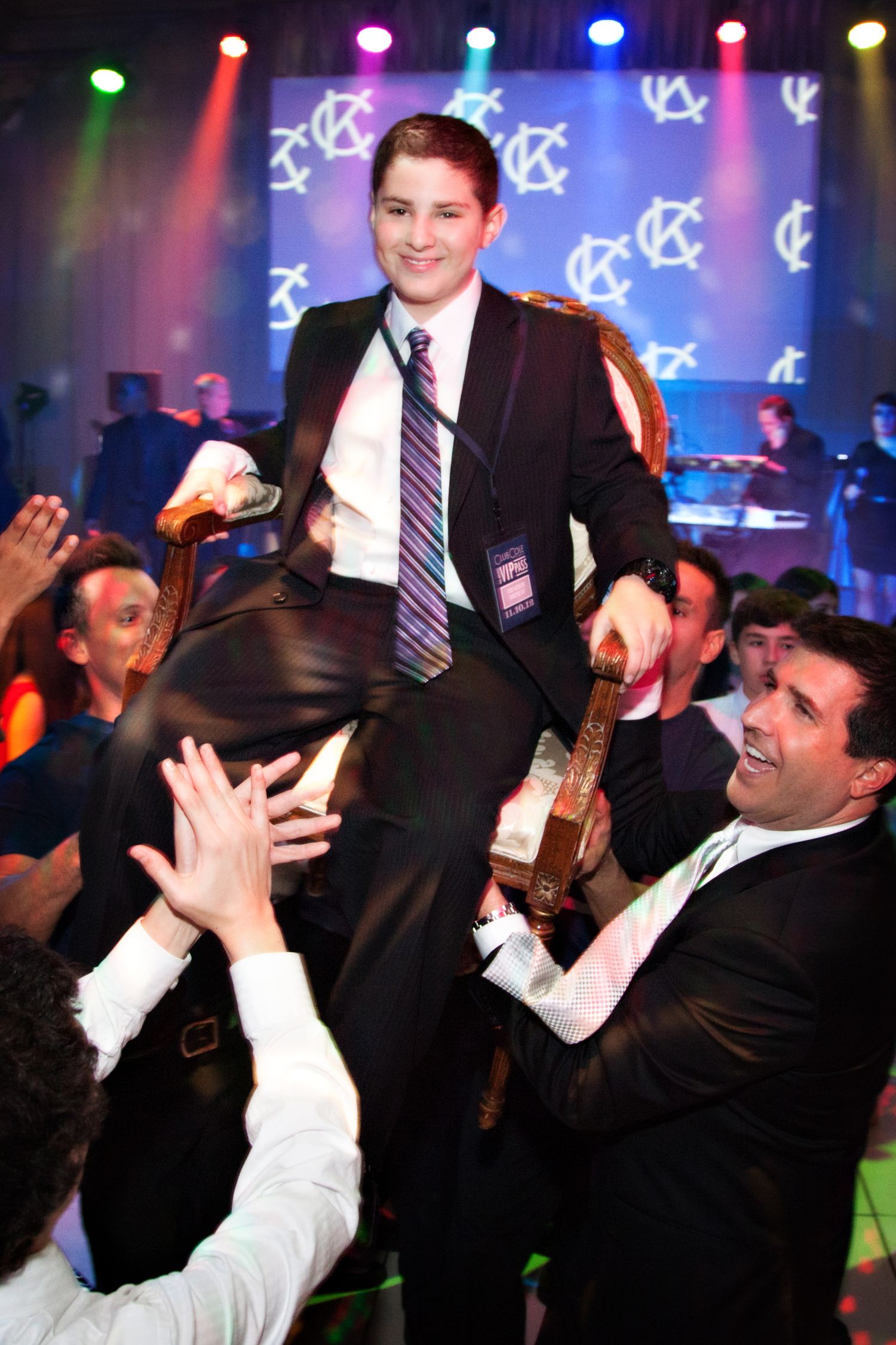Energetic performer engages with crowd during concert as audience reaches toward stage under purple lighting.
