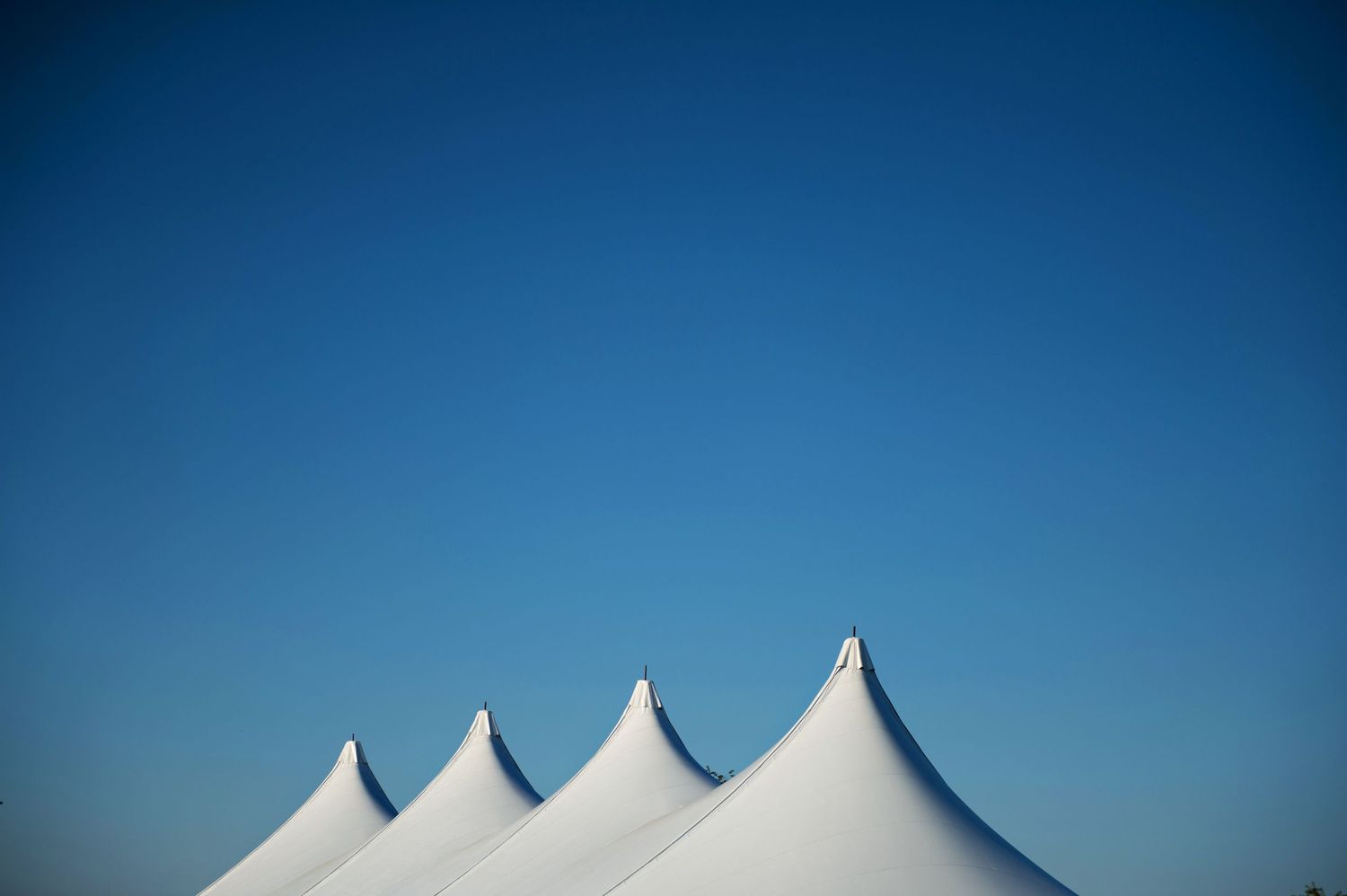 White tent peaks against a clear blue sky forming geometric shapes.