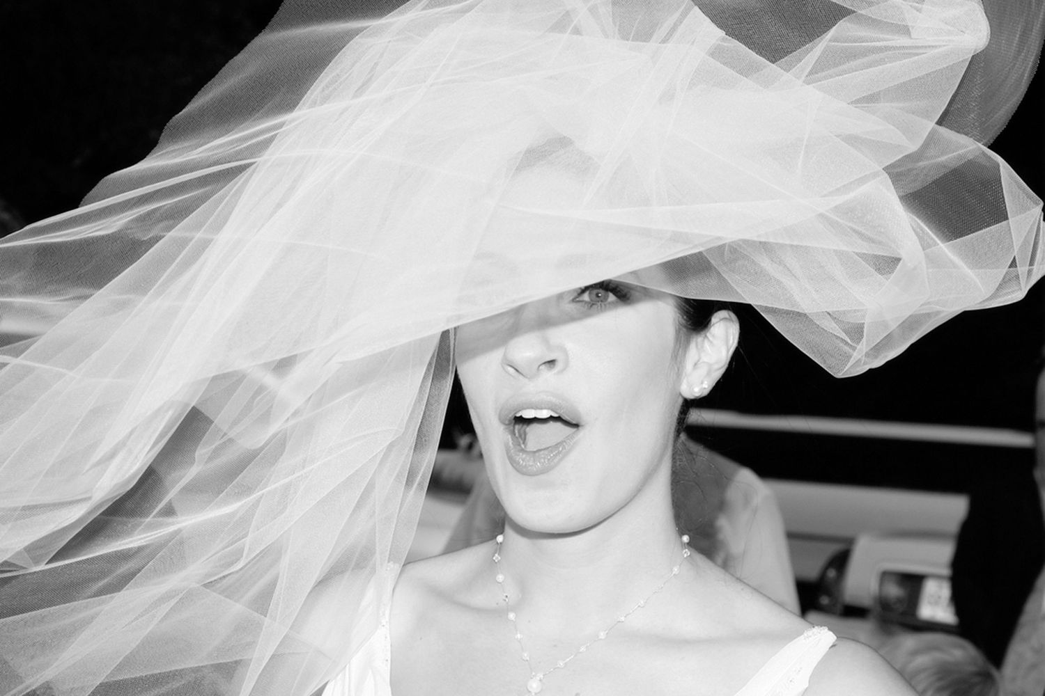 A black and white photo series showing a bride in a flowing veil with dramatic lighting and different poses.