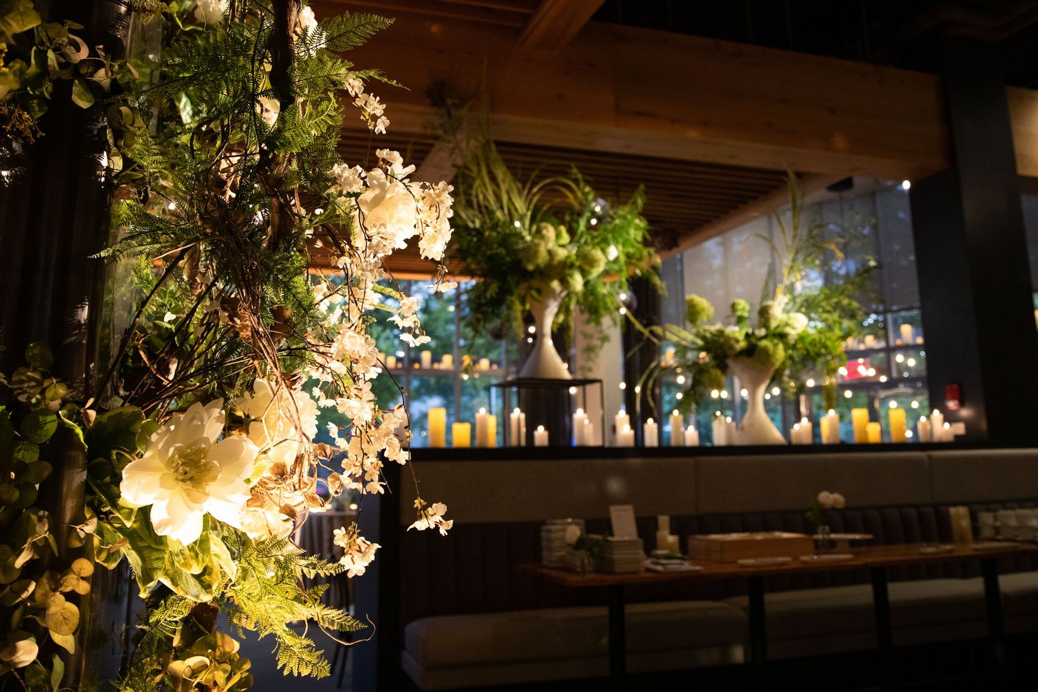 Moody bar interior with dramatic floral installations and backlit bottle display.