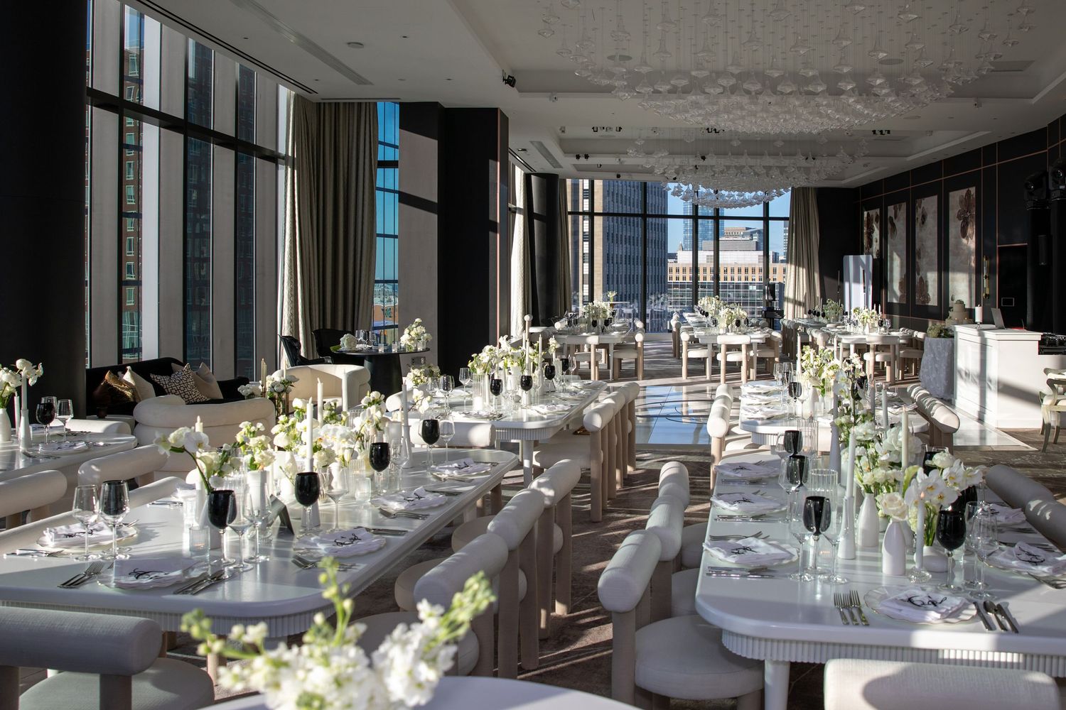 Modern reception hall with floor-to-ceiling windows and elegant white table settings.