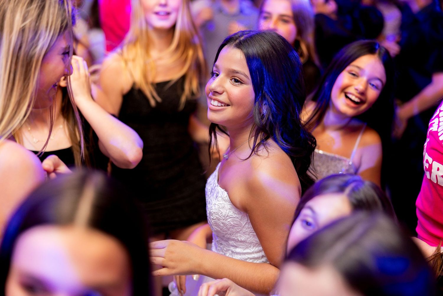 Dancing partygoers enjoying themselves under colorful party lights.