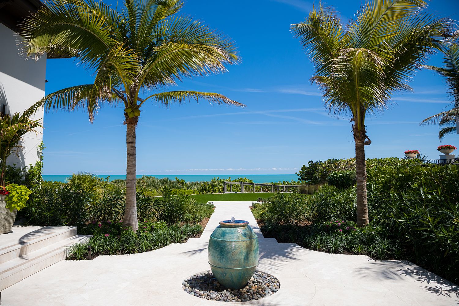 Decorative garden urn between two palm trees overlooking ocean view landscape.